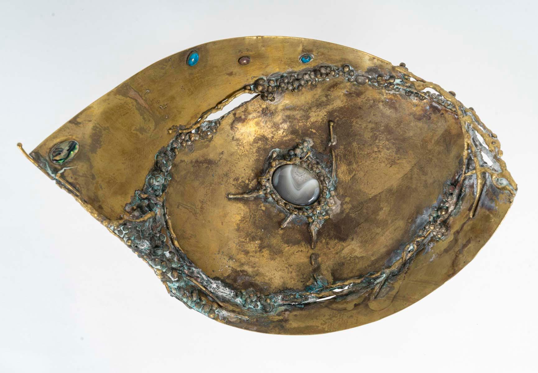 Ciotola in ottone con intarsio di pietre semi-preziose, 1960.

Una ciotola in ottone del 1960 con intarsio di pietre semi-preziose.
H. H. 22 cm, L. 30 cm, P. 21 cm.