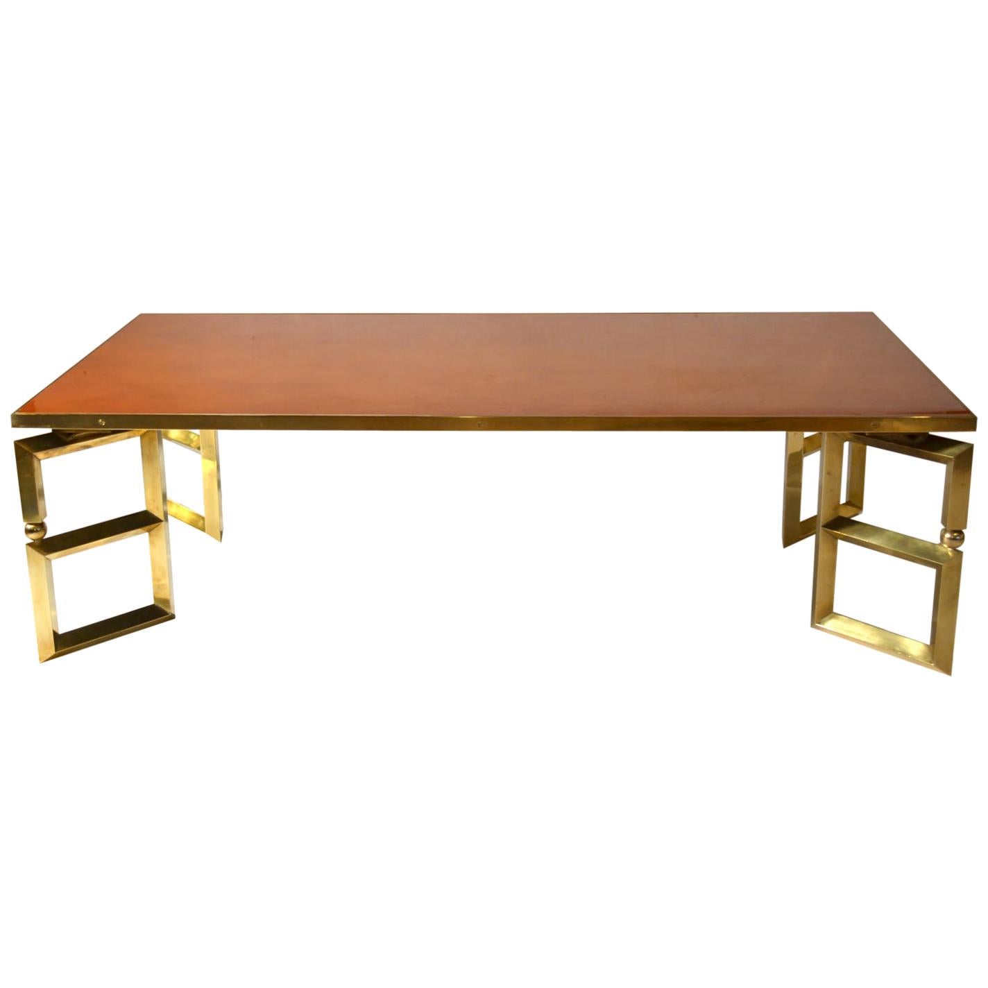 Sophisticated rectangular 1970s coffee table attributed to Guy Lefevre, signed Maison Jansen, Paris. The brass edged table has a burned orange lacquered wooden top inserted. Four brass legs are placed in a cross pointing outwards to the corners to