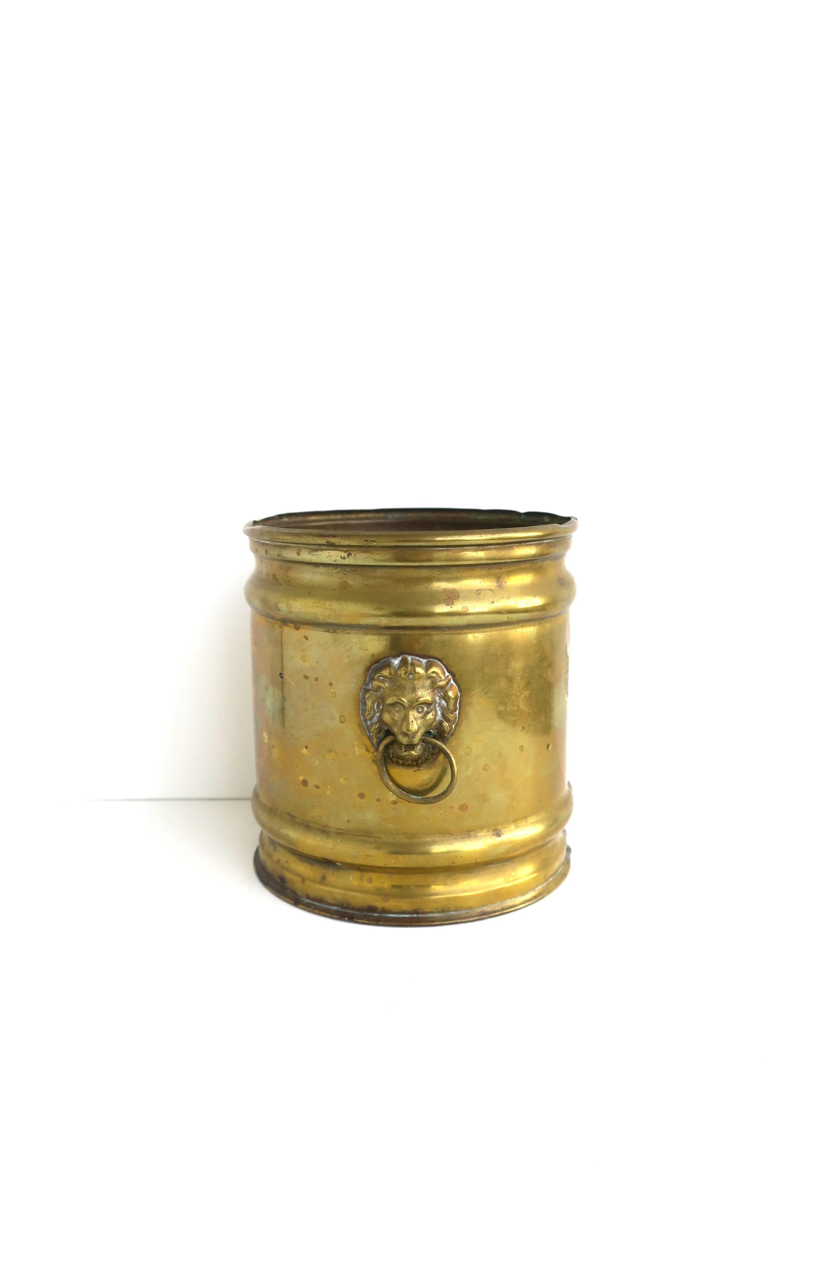 An English brass planter cachepot jardinière with Lion head and loop/ring design, circa mid-20th century, England. A great small piece with Lion head on sides (or front/back, depending on which way you choose to display.) Great as a standalone piece