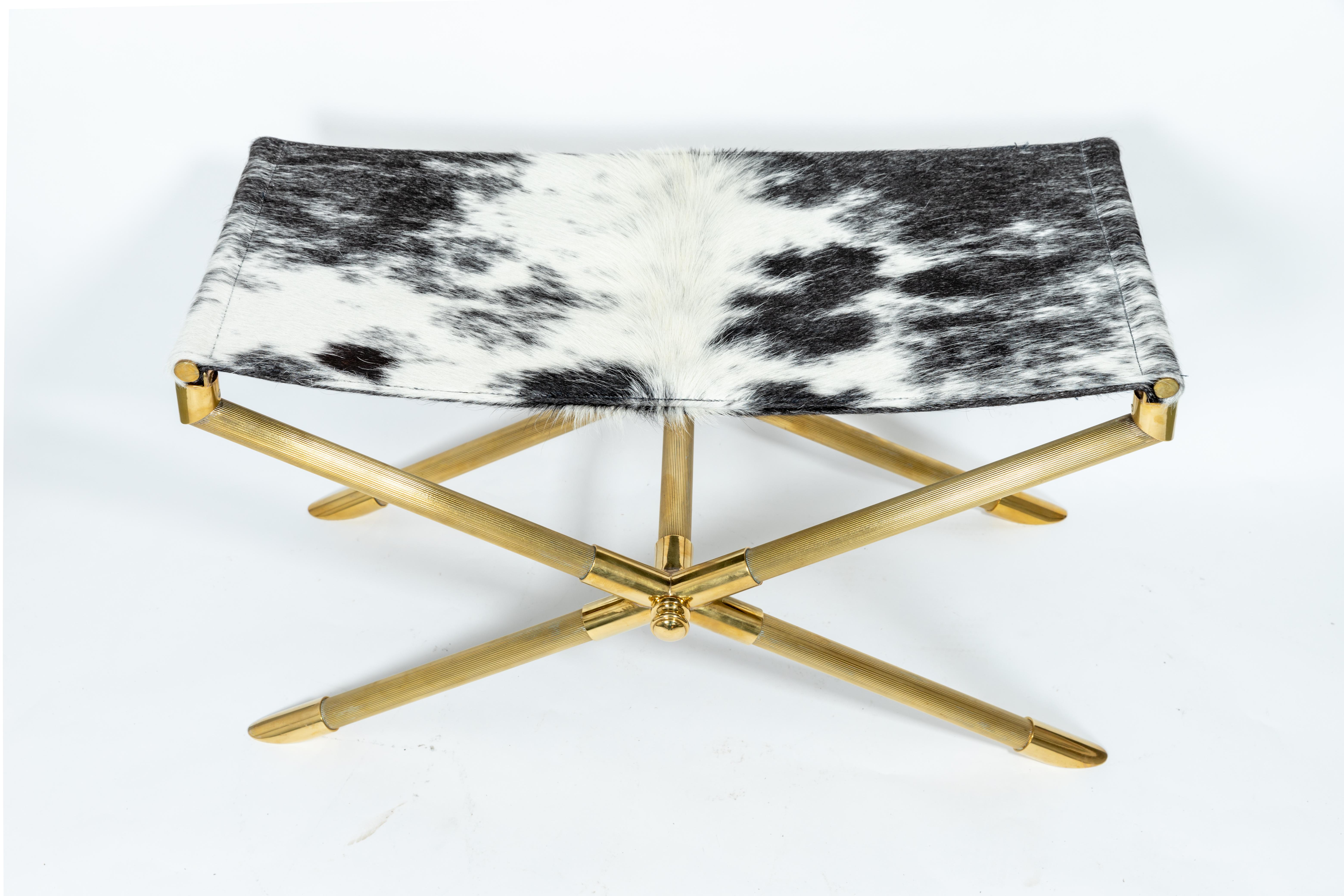 Brass Campaign style bench with cowhide strap seat.