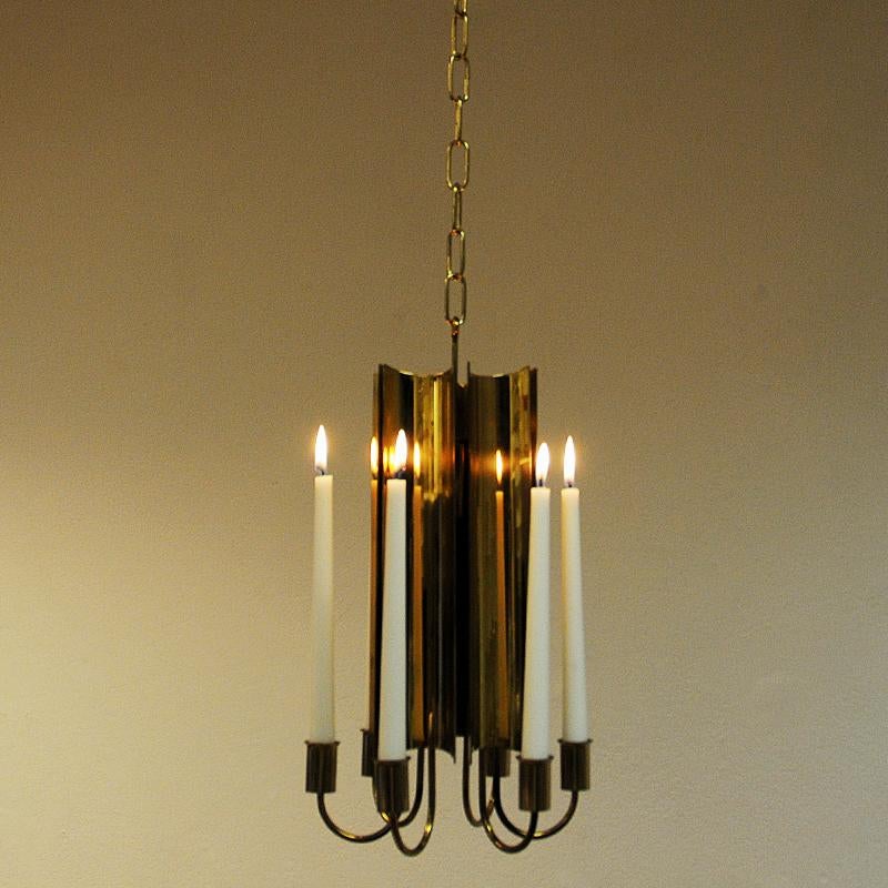 Stunning and elegant midcentury brass candle chandelier with six candleholders by Pierre Forssell for Skultuna, Sweden, 1960s. The six candleholders have a brass back shield giving a calm and relaxing light into your room when the candles are lit.
