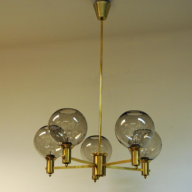 Beautiful ceiling lamp in the manner of Hans-Agne Jakobsson consisting of a polished brass stone and smoke colored glassdomes. The ceiling lamp has 5 beautiful glassdomes with small enclosed airbubbles inside which delivers a really nice light. This