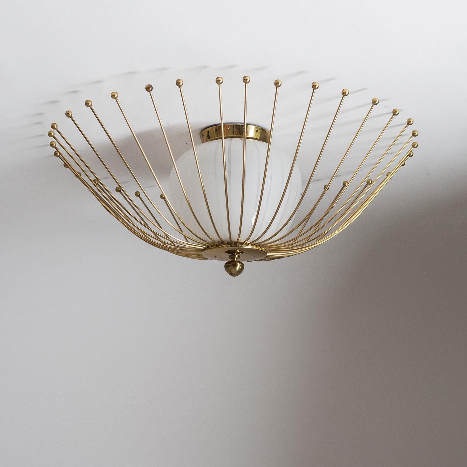Rare brass and glass flush mount from the 1940-1950s. A satin glass diffuser with clear stripes is surrounded by a polished brass cage consisting of a multitude of curved brass wires, each with a brass ball at the end which hovers just slightly