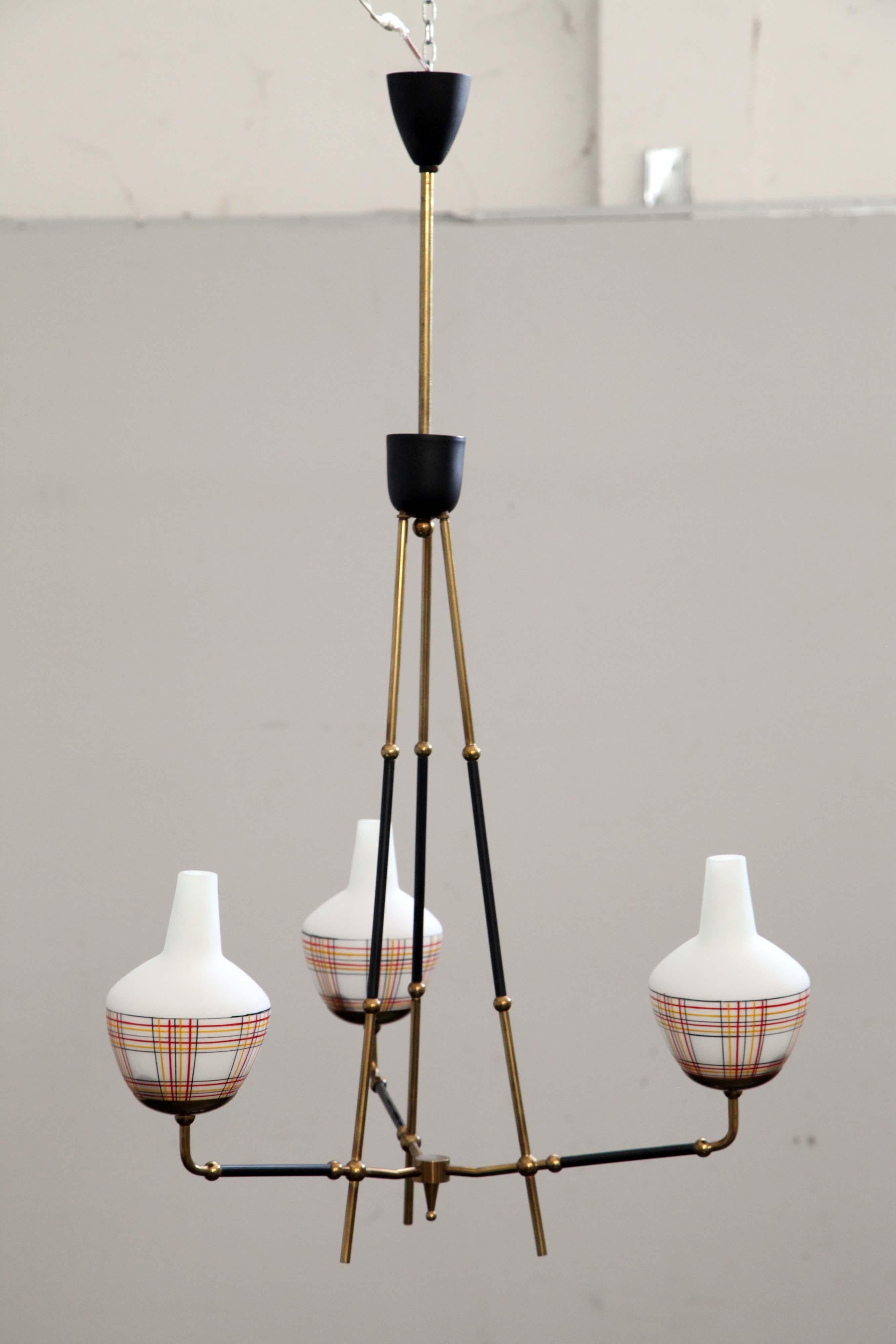 Lampadario in ottone lucido con giunti a sfera e parti laccate nere, diffusori in vetro opalino duplex bianco, con contributi di linee decorative in rilievo policrome. Attribuibile ad Angelo Lelii Arredoluce.
L'imballaggio con pluriball e scatole di