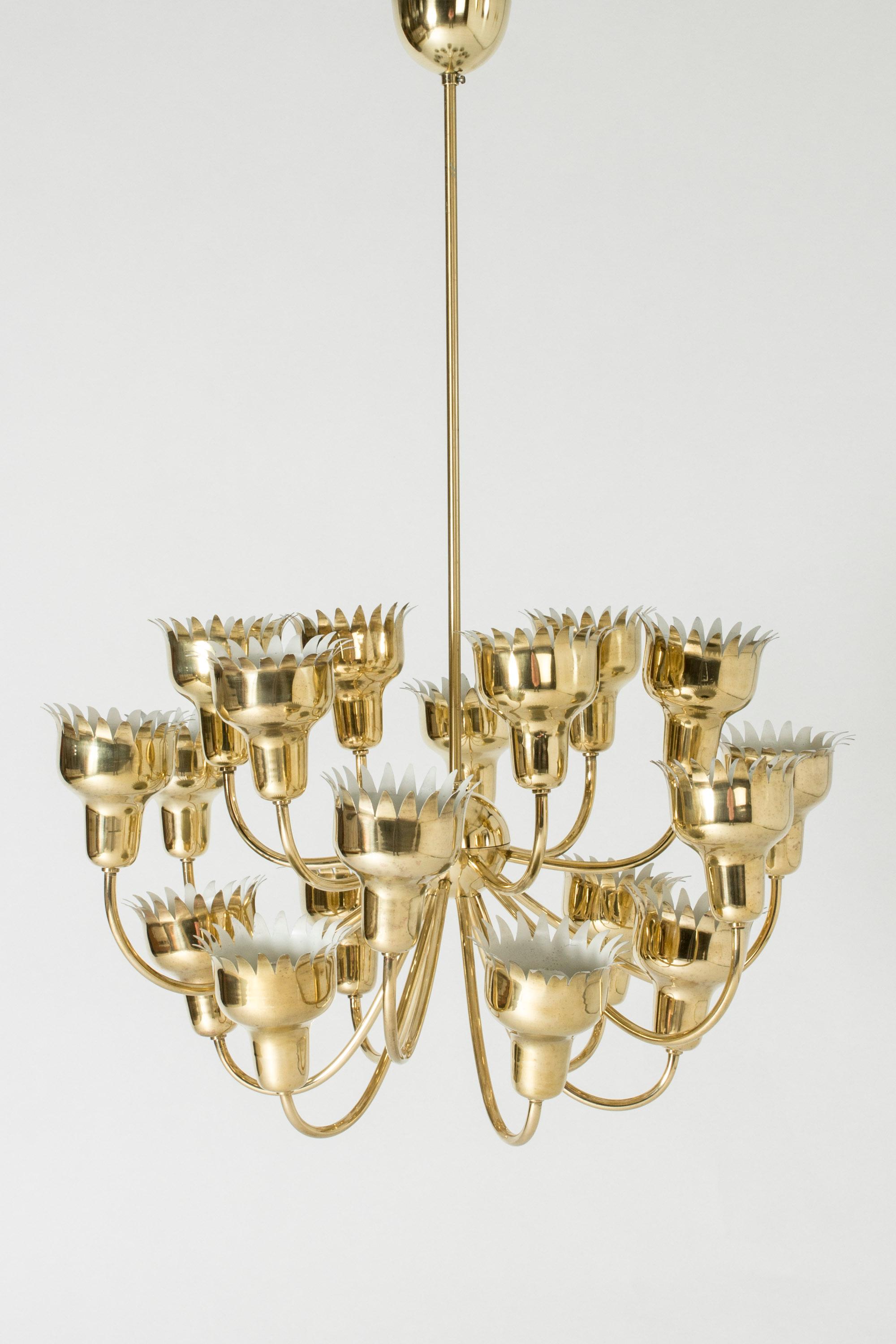Stunning brass chandelier by Hans Bergström. Eighteen arms abundantly extending upwards holding cups with zigzag edges, like flowers opening to the light.
