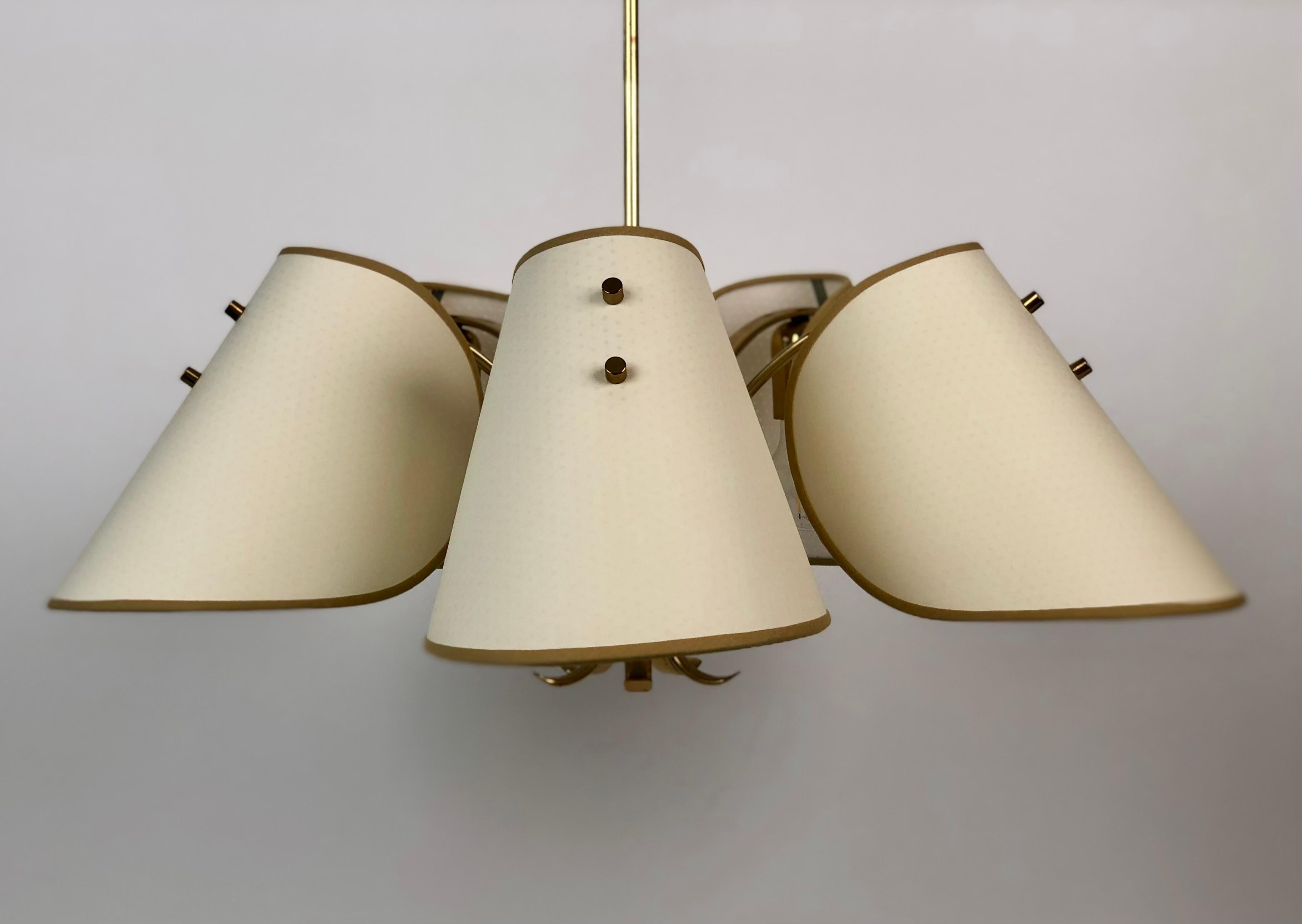 Lampadario in ottone con cinque paralumi prodotto dall'azienda austriaca Rupert Nikoll intorno al 1960.
Il corpo è in ottone massiccio; i paralumi sono realizzati ex novo sulla forma originale in carta e folie perforata per un effetto luce speciale