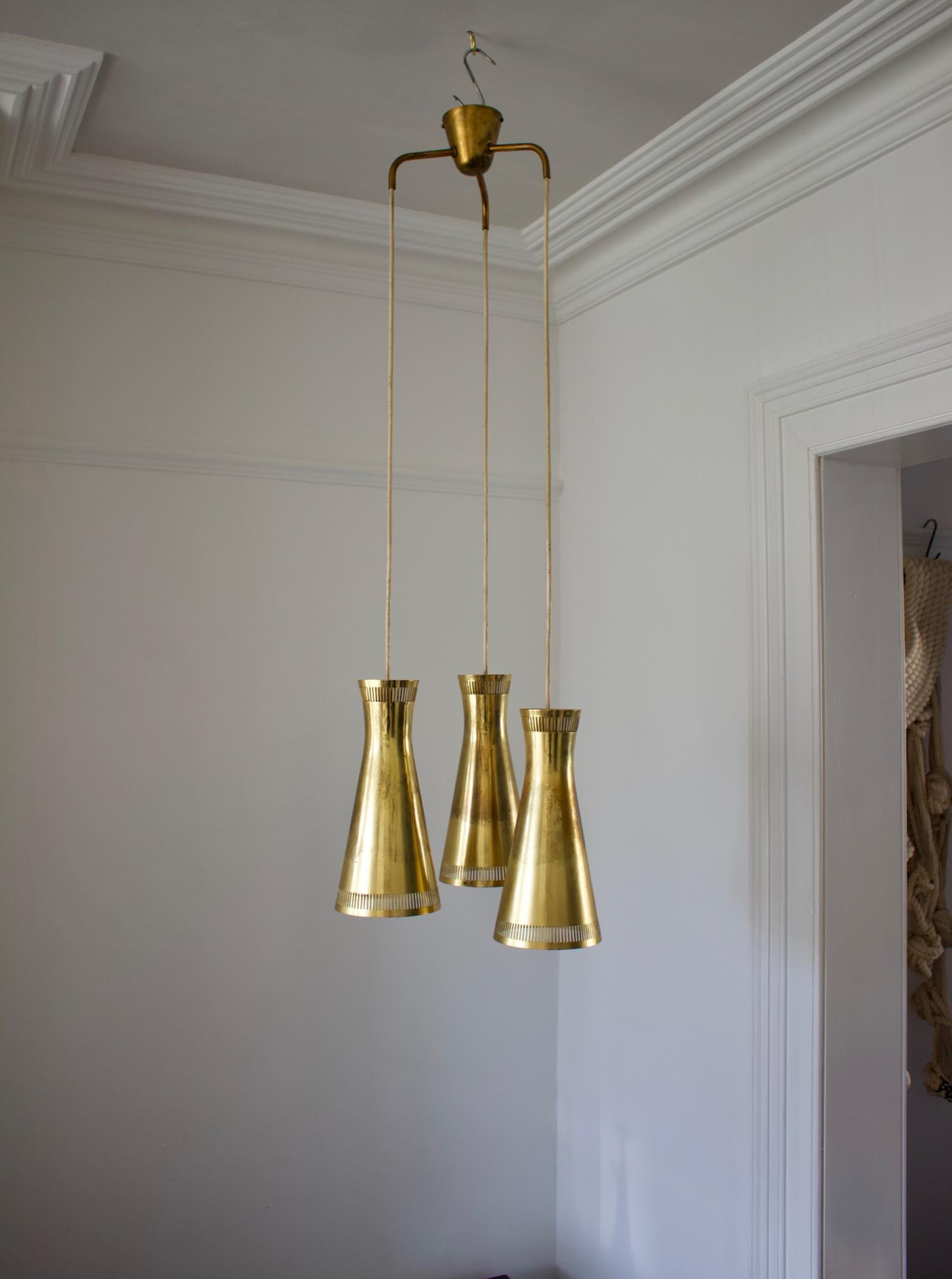 Brass chandelier by Itsu of Finland. Mid-20th century.

A high-quality cascading chandelier featuring three shades made of brass - white on the inside - arranged at different heights. The original ceiling canopy is in place and the fixture has the