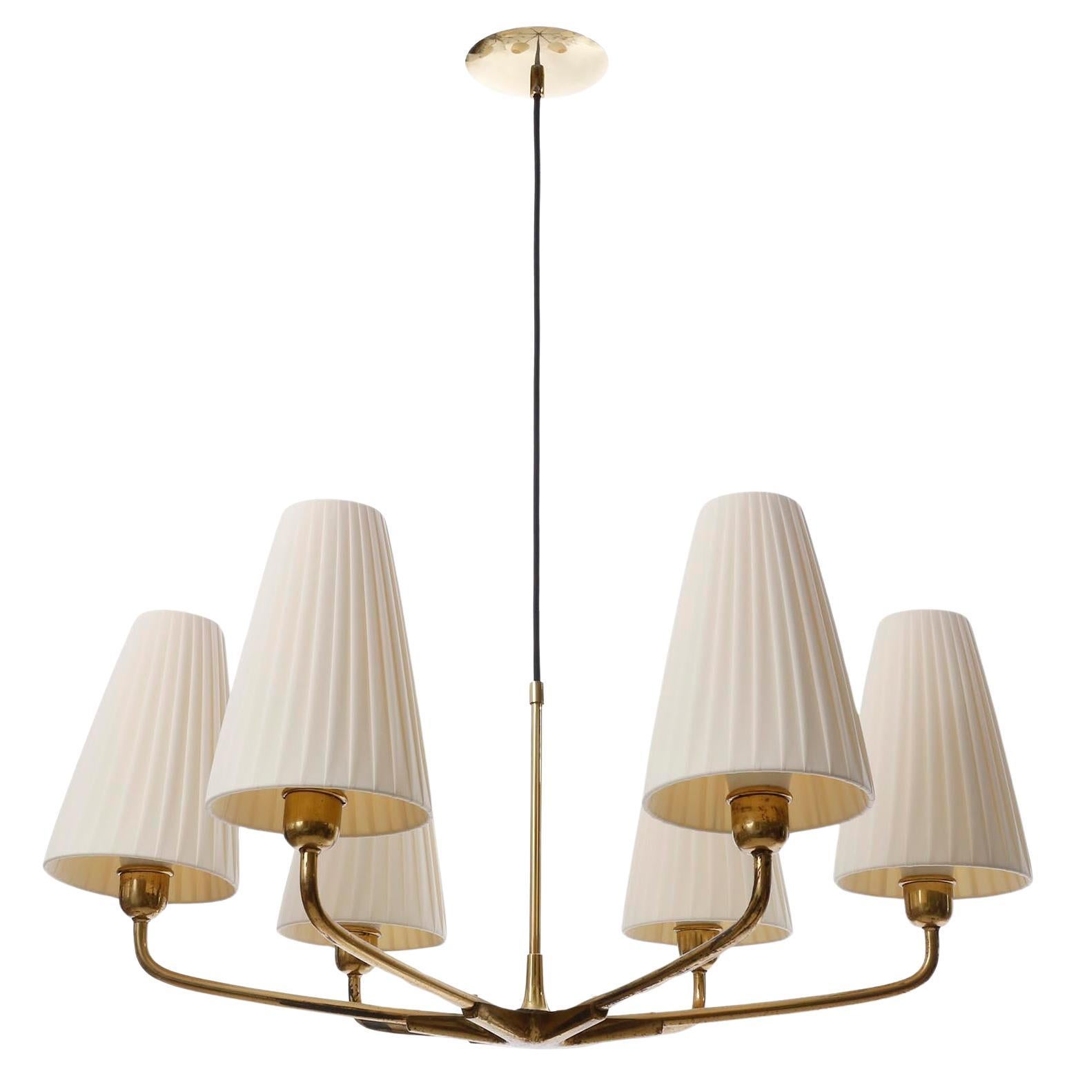 A fantastic pendant light manufactured in Austria in 1930s.
The fixture is made of brass with six curved arms with cream-colored pleated fabric shades.
The brass parts have patina, wear and a warm aged hue. They can be repolished for free of