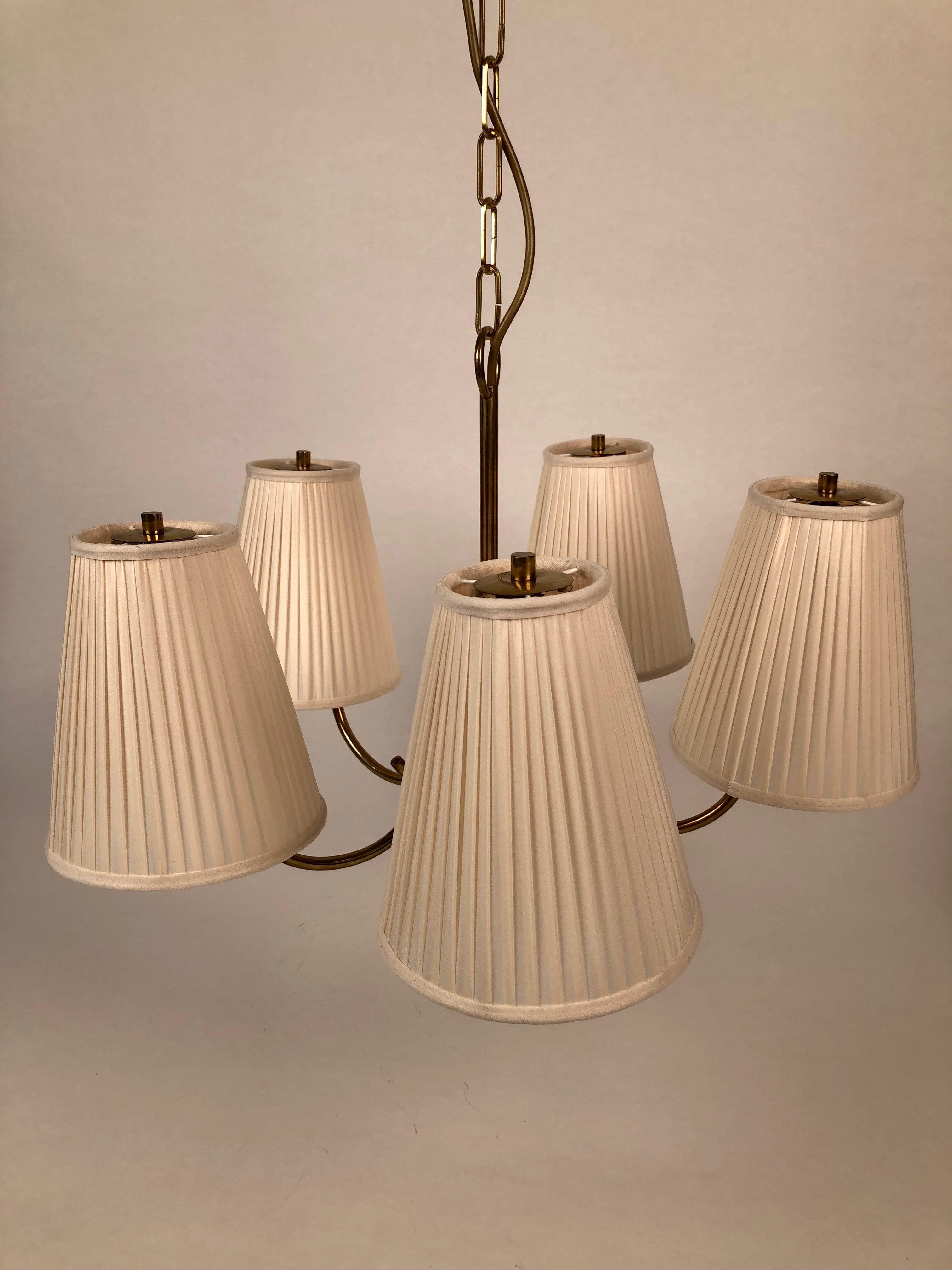 Elegant brass chandelier made in Austria, from the firm Nikoll in a decorative style from the 1950s.
The five arms are decorated with new silk shades, in cream color.
The lamp is rewired.
  
