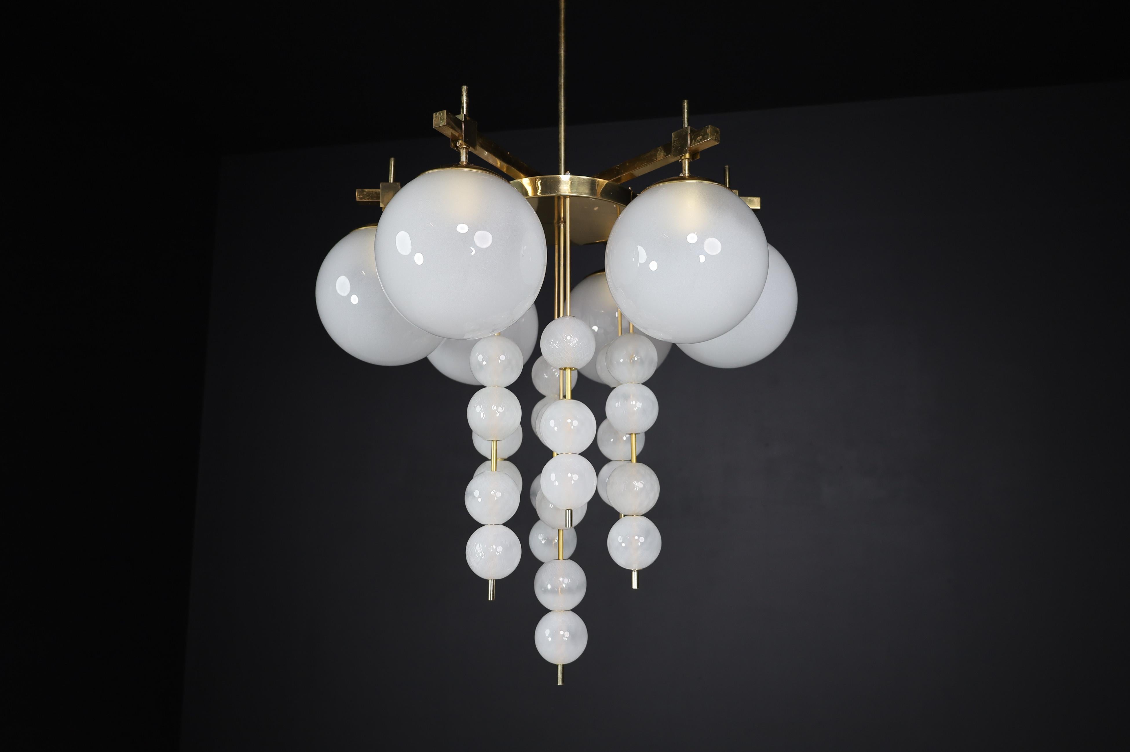 Brass chandelier with frosted glass globes, Czechia 1950s

A large chandelier with a brass fixture was produced and designed in Czechia in the 1960s. A total of six large frosted glass globes and multiple smaller structured frosted glass globes.