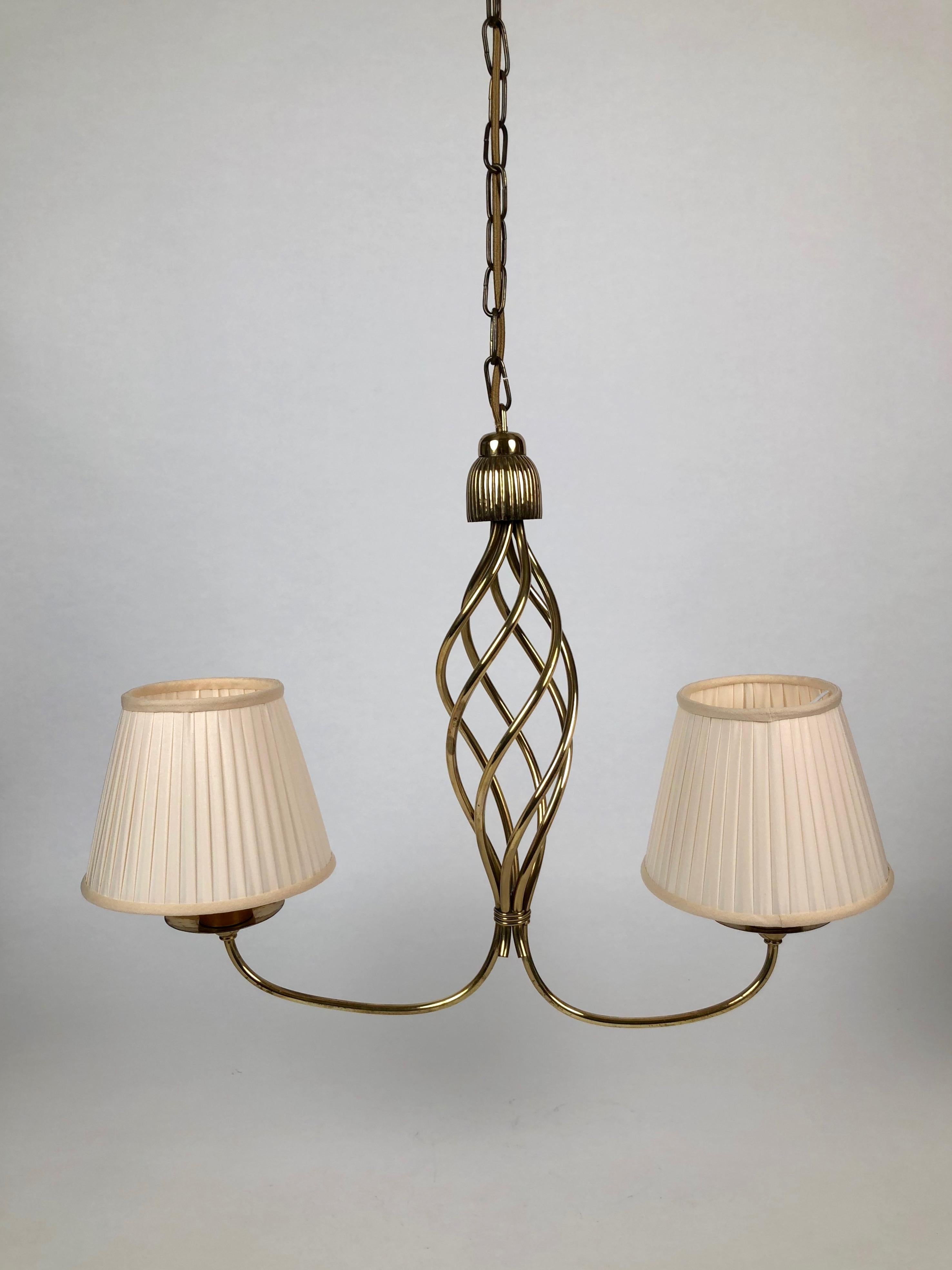 Beautiful handmade lamp from 1930s in brass. The braid is hand fabricated and the details are hand-hammered in brass.
The chandelier is asymmetrical in design and its completion represents Fine craftsmanship.
The shades are new in cream silk.