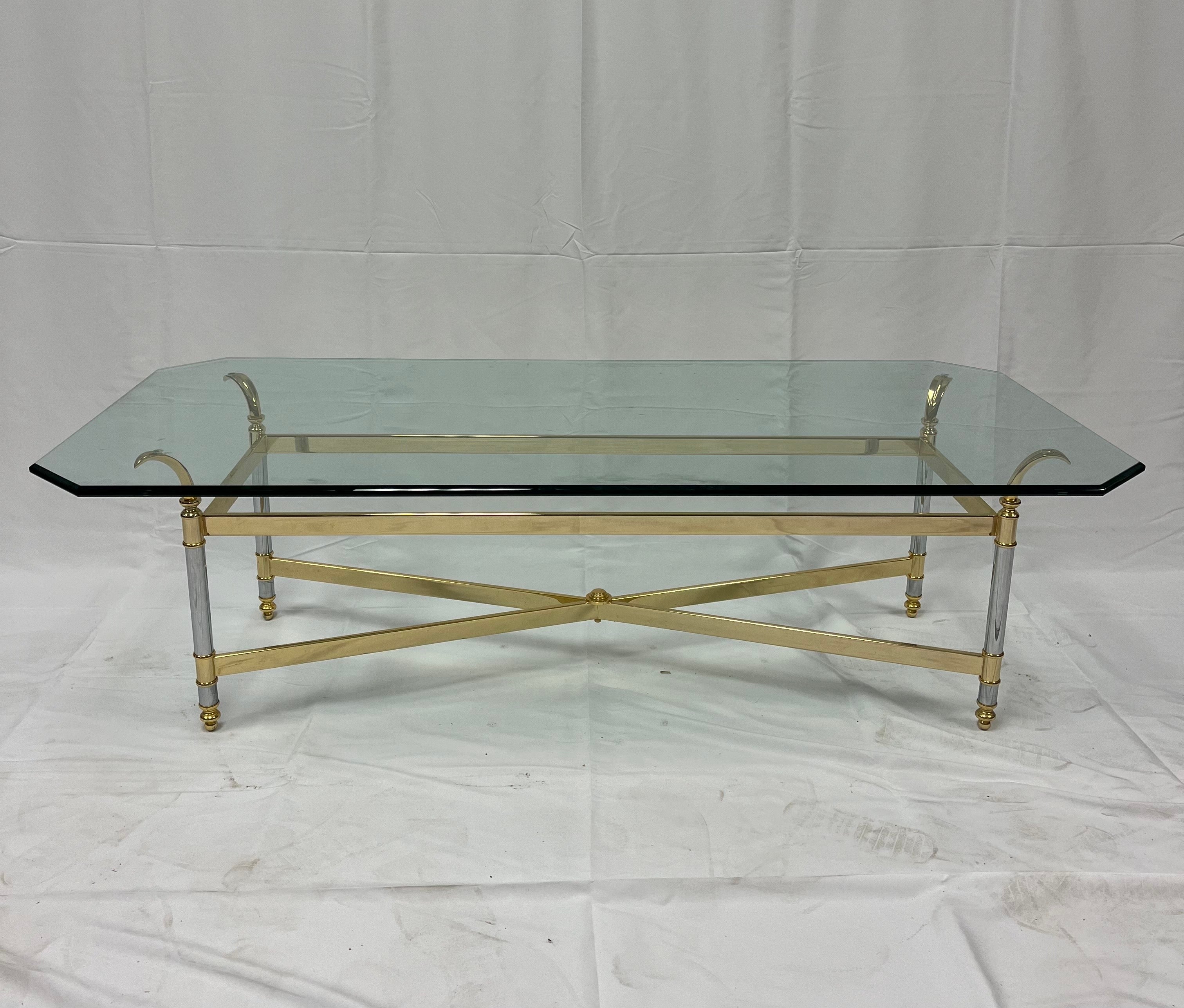 Table basse ou table de cocktail française sophistiquée avec une superbe structure en laiton et chrome avec un beau design graphique et des accents chiques. Le verre a des faces à facettes et est très épais. Cette table rectangulaire solide et
