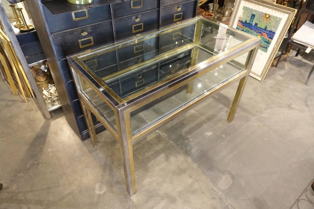 Gorgeous vintage boutique display table (montre), from France. A super elegant combination of brass, glass and chrome. Two sliding door partitions to present items.

Provenance – a Parisian jewellers.

A fabulous piece for display purposes