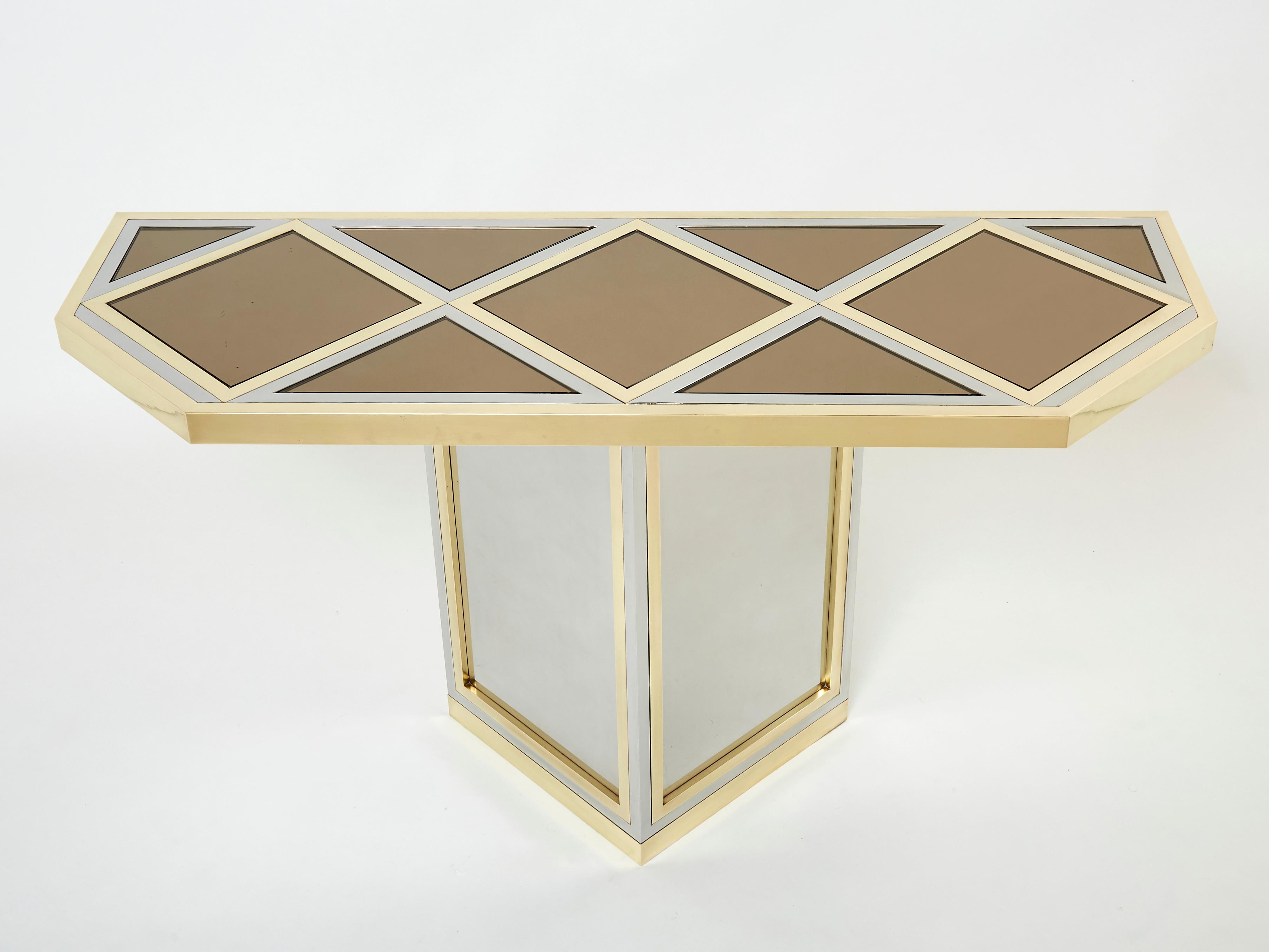 A beautiful piece of design, this console table deserves to be the focal point of your entrance or living room. Symmetrical brass and chrome elements strike through a geometrical smoked mirror top, the result being an impressively sleek decorative