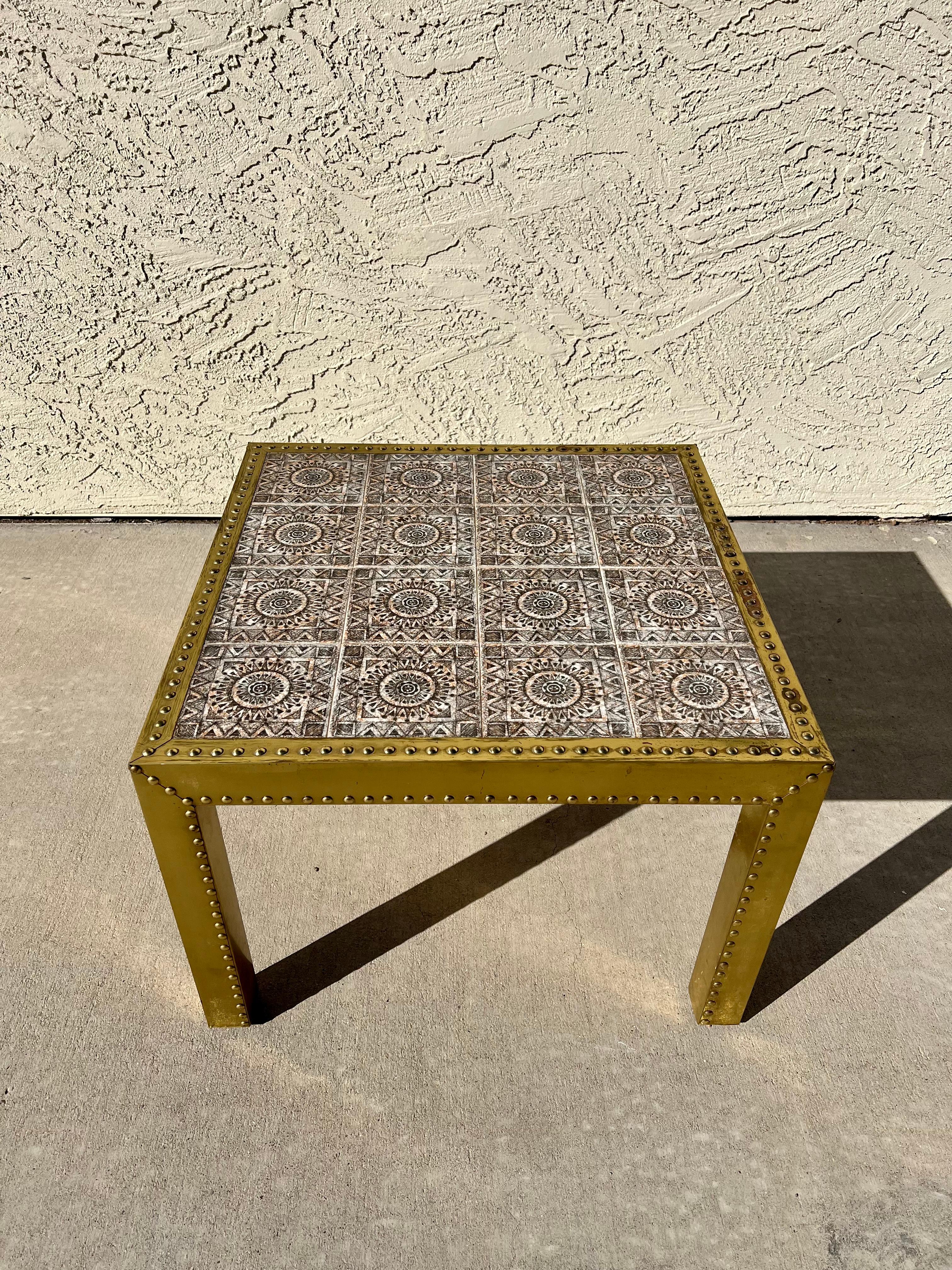 One of a kind, never seen another brass clad studded with handpainted mosaic tile top coffee/cocktail/large side table. Very nice vintage condition with some minor corrosion to the top of the brass but overall presents beautifully and the patina is