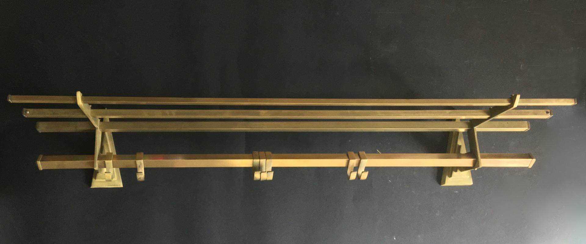 Wall-mounted brass coat rack with hat shelf. European, early to mid 20th century, in art deco or machine age style. 

Raw brass coat rack with seven cast hooks and an angled hat shelf. Nicely engineered with cast brass triangular brackets and