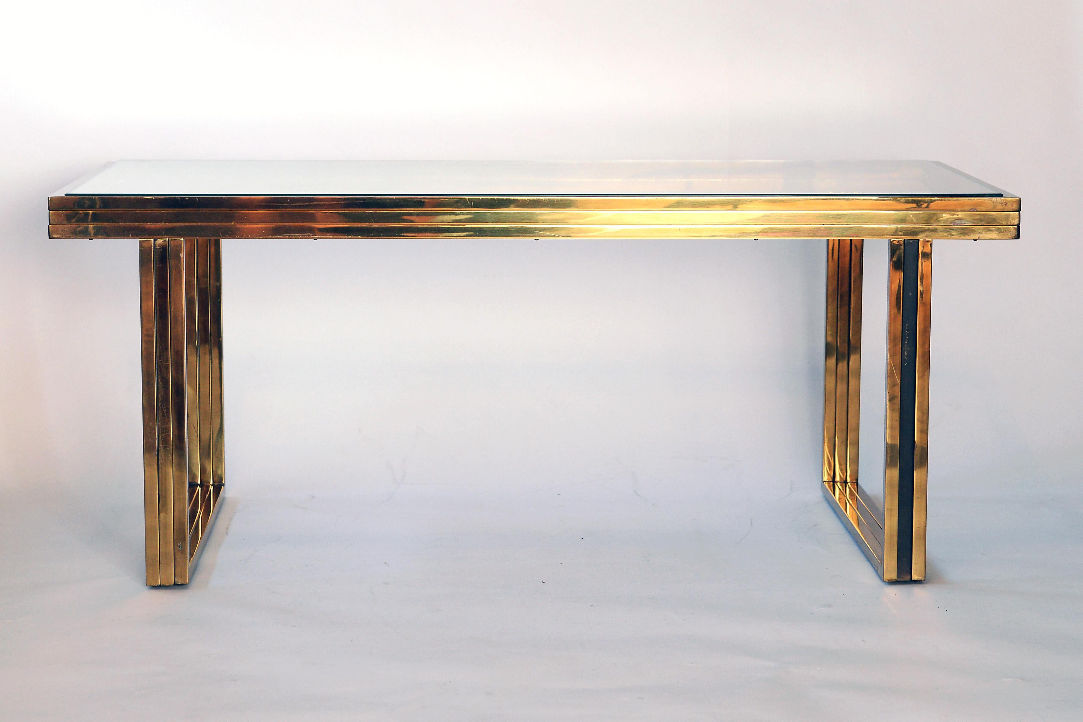 Elegant brass and glass top coffee table by Romeo Rega.

The table is in original untouched condition with patinated brass.

The glass has some minor chips in the corners, but can be replaced on demand with another clear glass, smoked glass or