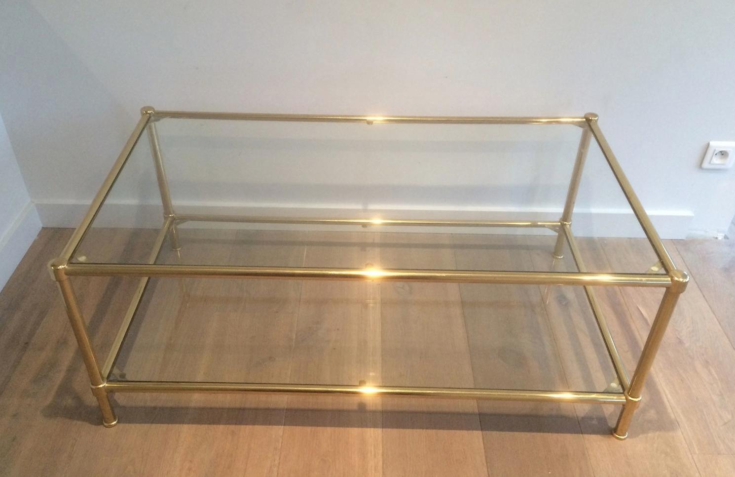 This nice coffee table is made of brass with 2 clear glass shelves. This is a French work, circa 1960.