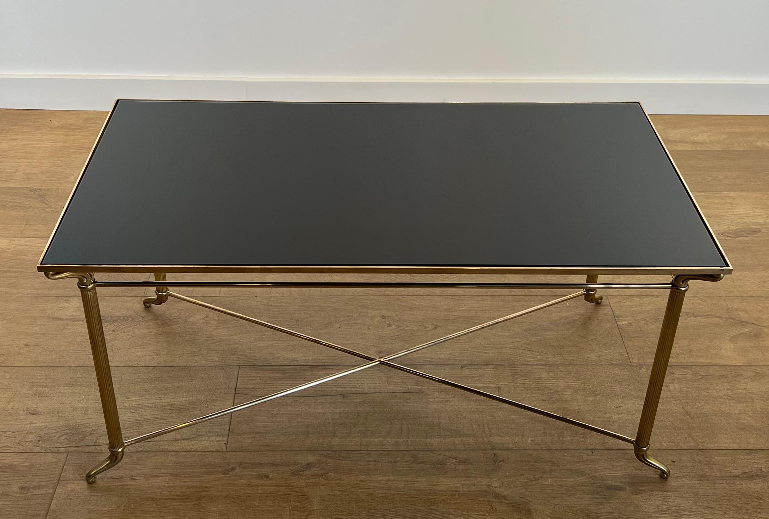 Cette belle et élégante table basse rectangulaire est fabriquée en laiton avec un plateau en verre laqué noir. Il s'agit d'une œuvre française dans le style de la Maison Jansen. Circa 1940