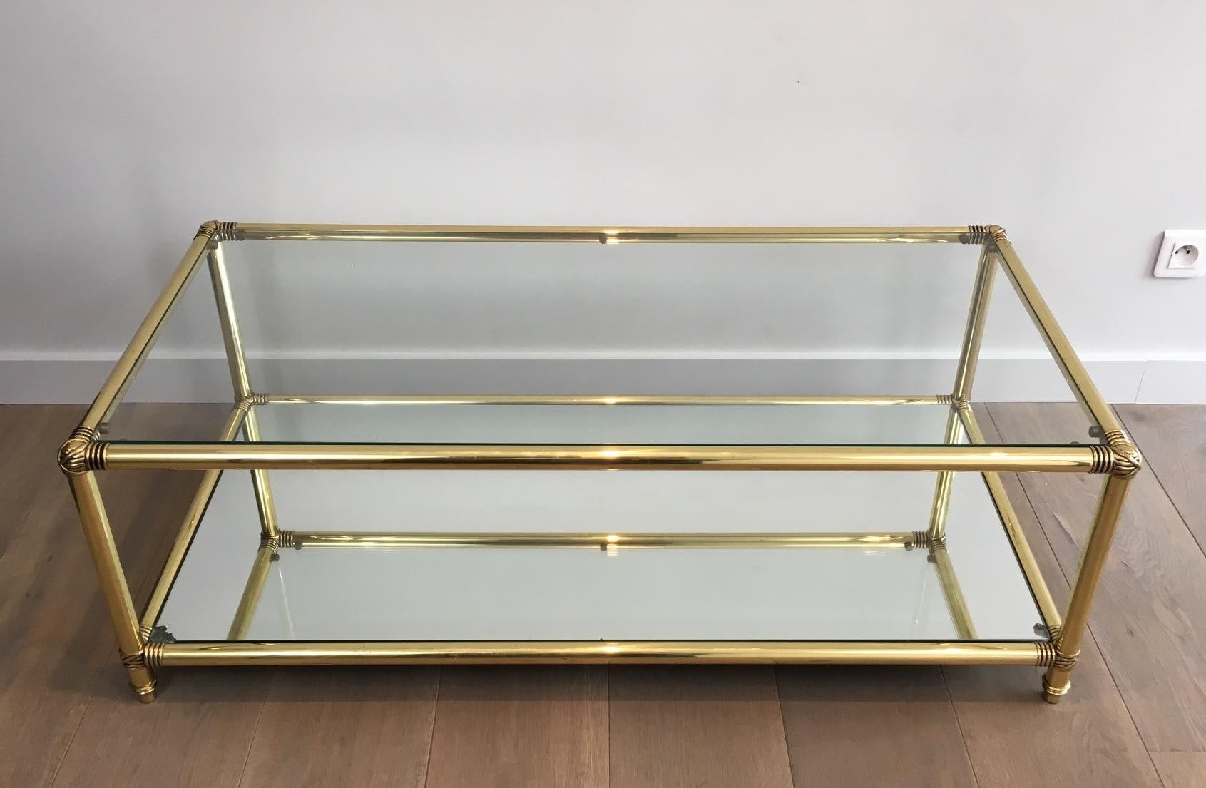 This elegant coffee table is made of brass. There are brass noddles on the corners, a mirror shelf on the bottom and a glass shelf on top. This is French, circa 1970.