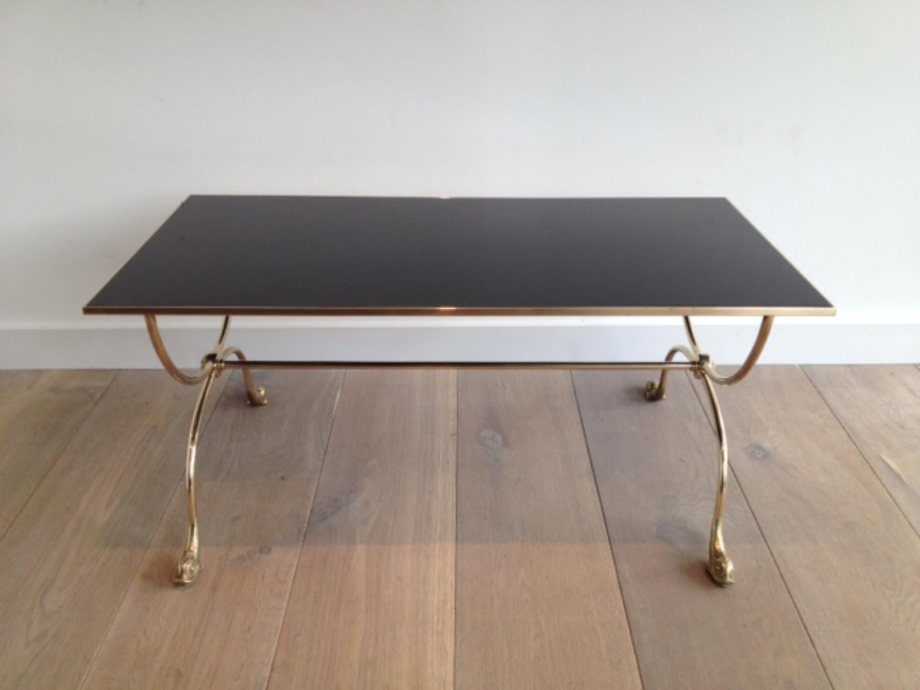 This coffee table with dolphin heads is made of brass with a black lacquered glass top. This is a French work by famous French designer Maison Jansen. Circa 1940.