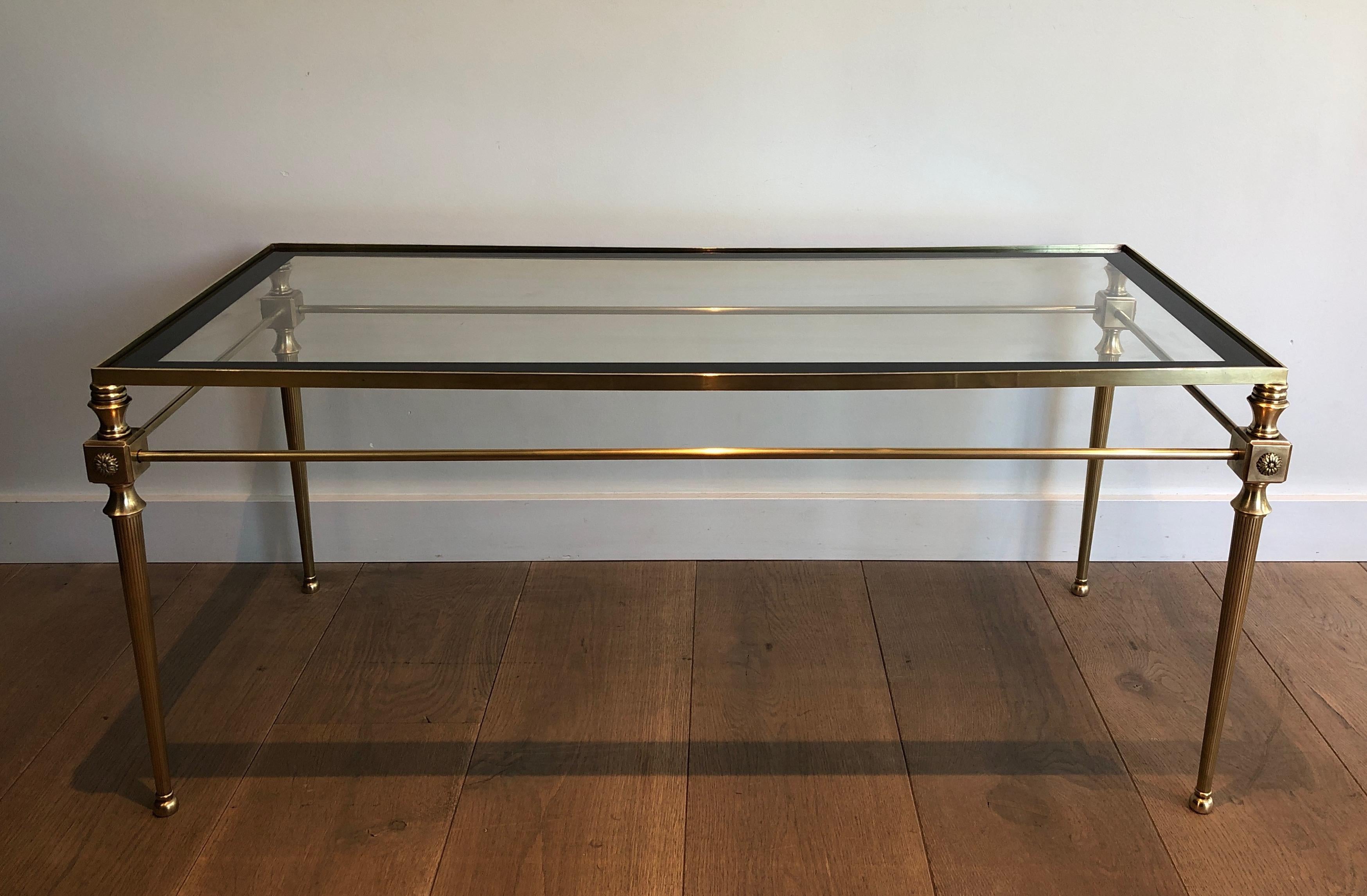 This neoclassical style coffee table is made of brass with glass top surrounded by a black lacquered line. This is a French work by Maison Jansen. Circa 1940.
 