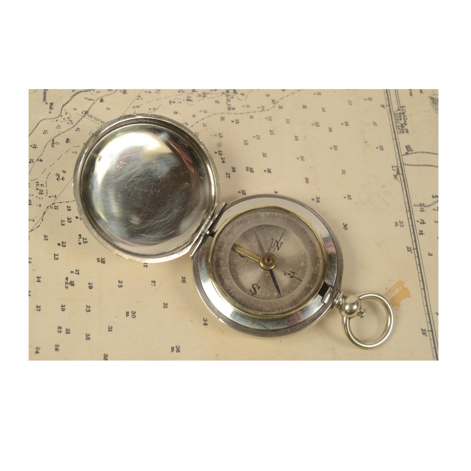 Pocket compass made of chromed brass in the shape of a pocket watch, and equipped with a lid with snap closure with release button inside the ring. Four-winds compass card complete with goniometric circle for calculating horizontal angles. Good