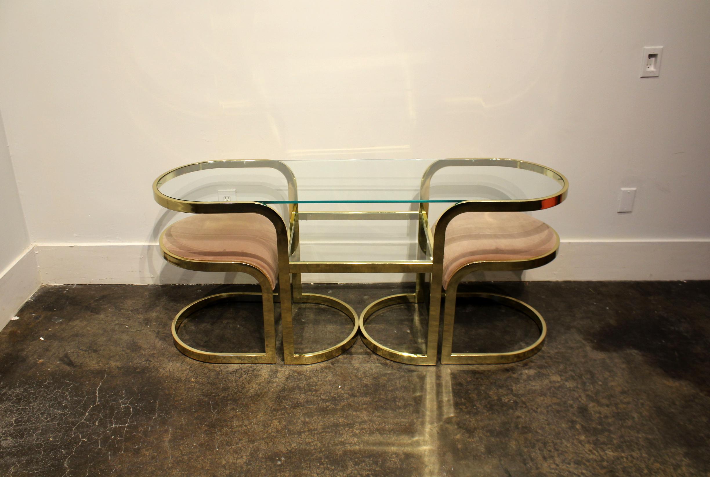 Really cute console table and chairs in brass chrome and glass. Has pair of brass stools in pink fabric that fit neatly underneath. Versatile design can be used as a console table, vanity, desk or cafe table. 

Table dimensions: 59.75