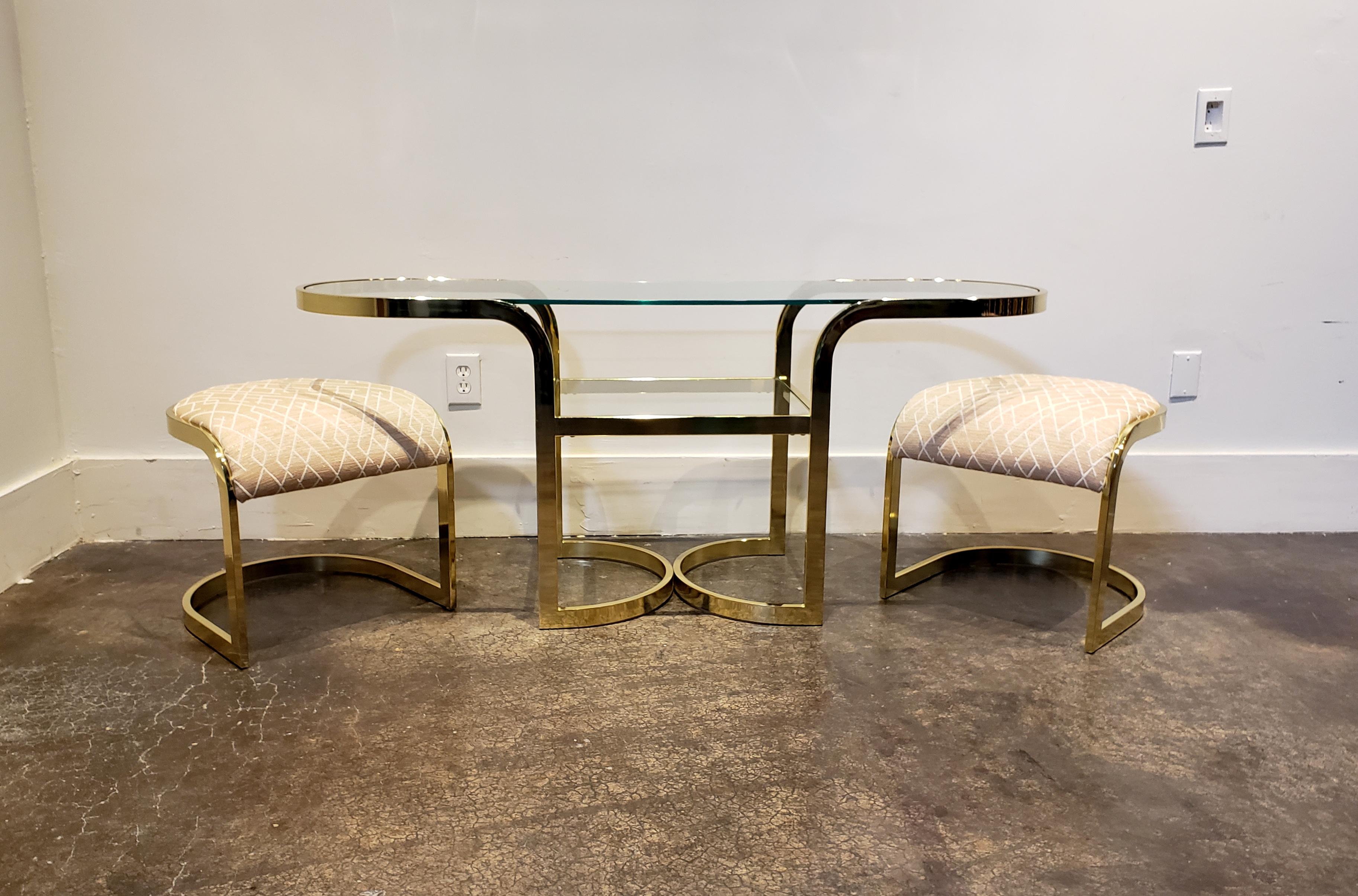 Really cute console table and chairs in brass chrome and glass. Has pair of brass stools in pink fabric that fit neatly underneath. Versatile design can be used as a console table, vanity, desk or cafe table. 

Measures: Table dimensions: 59.75