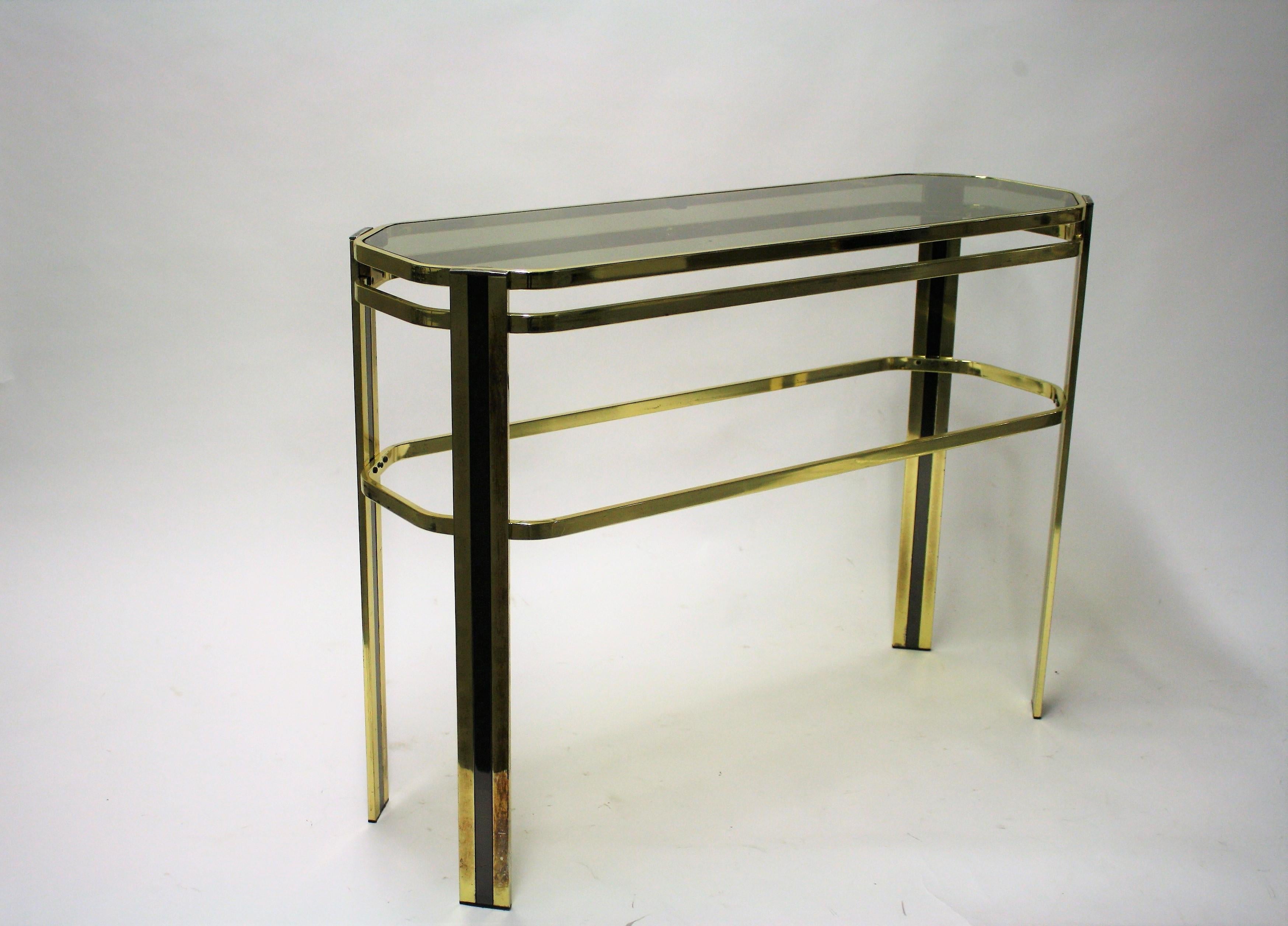 Vintage brass console table with a smoked glass top.

The console table is in original untouched condition, showing some patina.

It can of course be entirely polished if desired.

Good condition, original glass.

1970s,