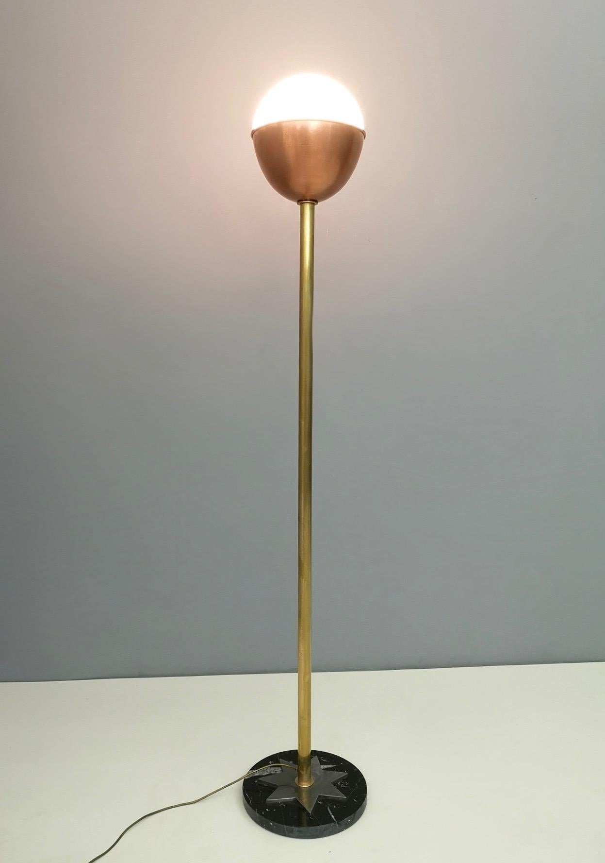 This floor lamp is made in brass, copper and encased glass and features a black marble base with an iron star.
It is in excellent original condition. 


