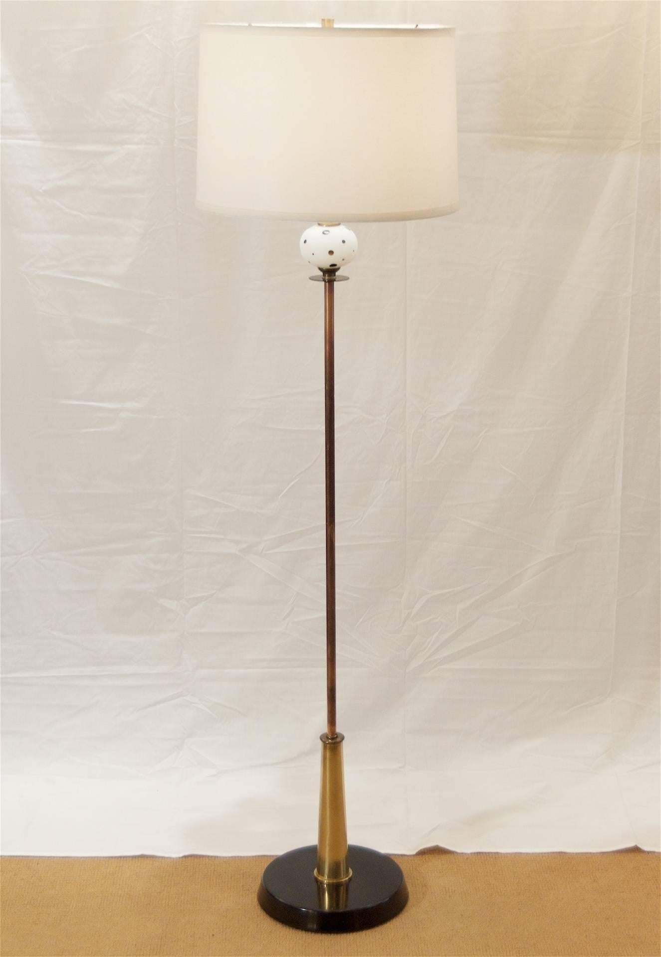 Unusual midcentury floor lamp of mixed materials; the base and accents in black enamel, brass and copper, with a decorative dotted glass bauble.

Single three-way bulb up to 150 watts, new wiring and socket.

Shade for demonstration purposes;