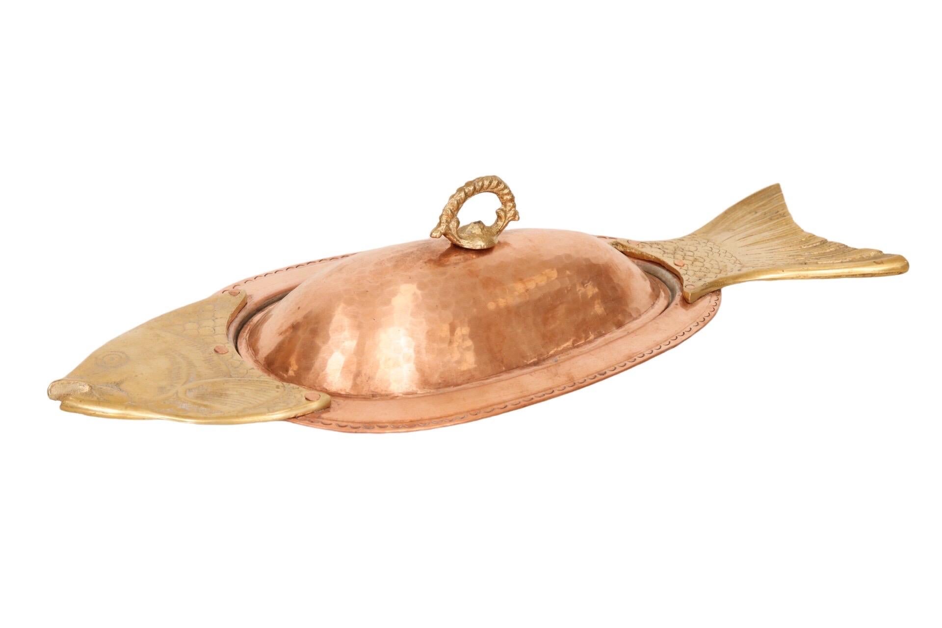 An oval serving platter made of copper adorned with a brass fish head and tail. Comes with a fitted copper lid.