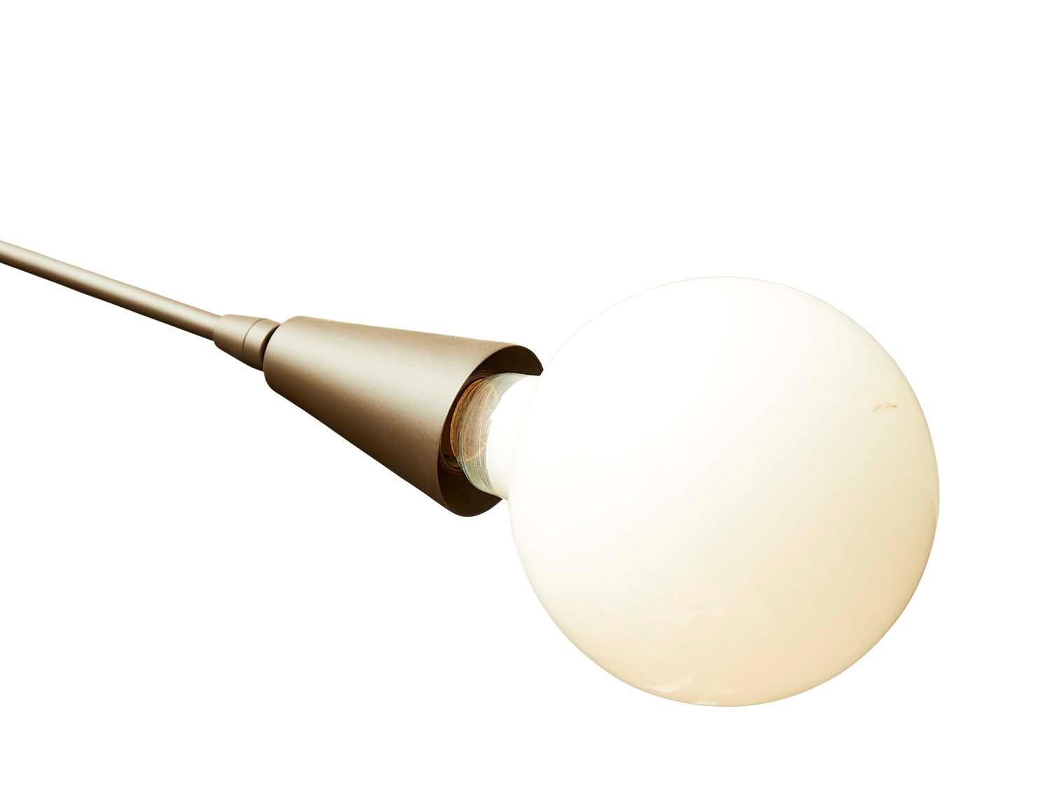 Il lampadario a contrappeso è caratterizzato da un'asta in ottone delicatamente bilanciata da un terminale in ottone su un'estremità e da una grande lampadina sull'altra. Il lampadario è disponibile nelle finiture in ottone o in metallo verniciato a