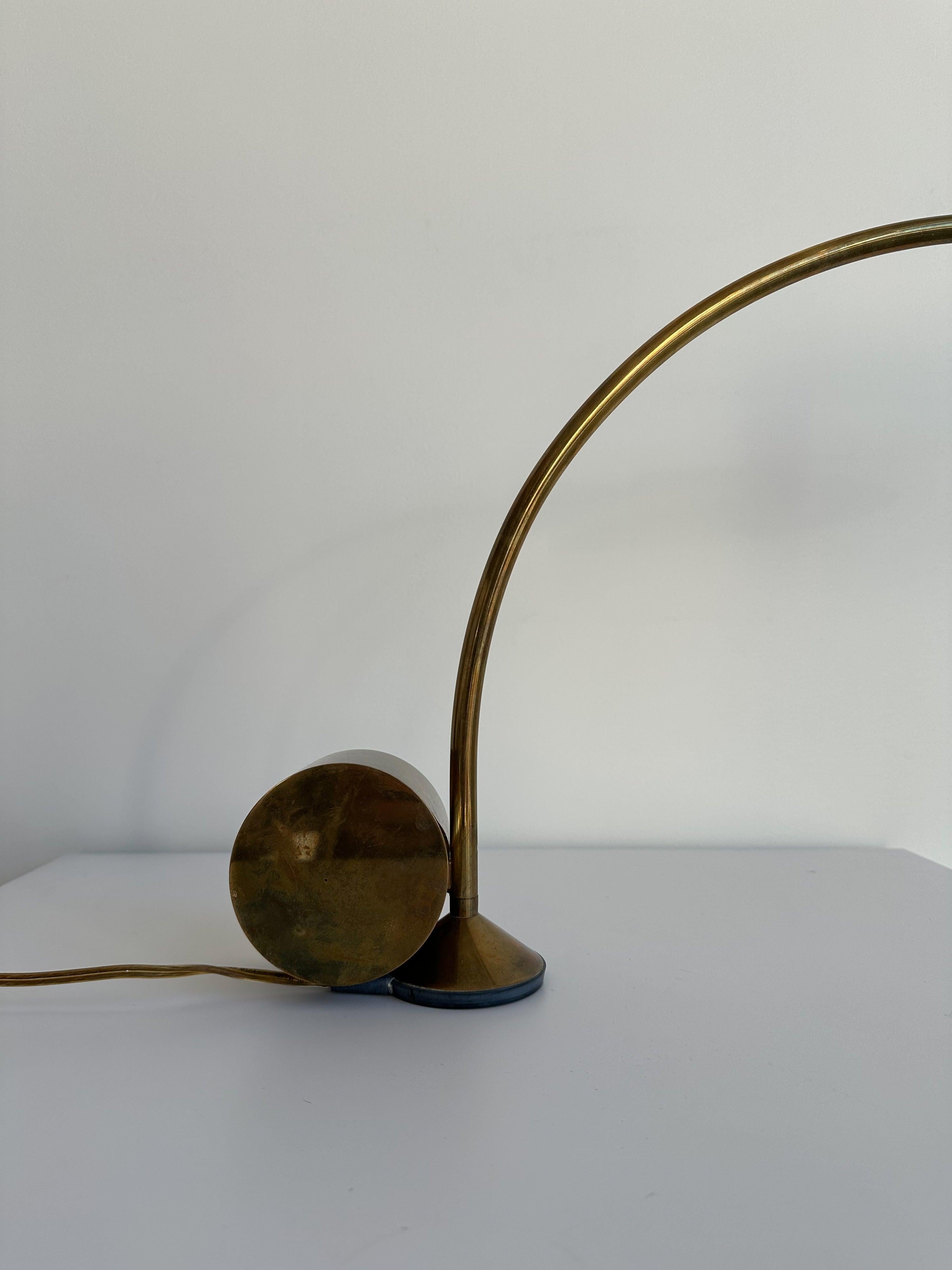 Lampe de bureau de génie à contrepoids en chrome, avec un abat-jour arrondi et un bras chromé incurvé. La lampe tourne sur une base ronde en nylon avec un contrepoids suspendu qui soutient l'abat-jour.