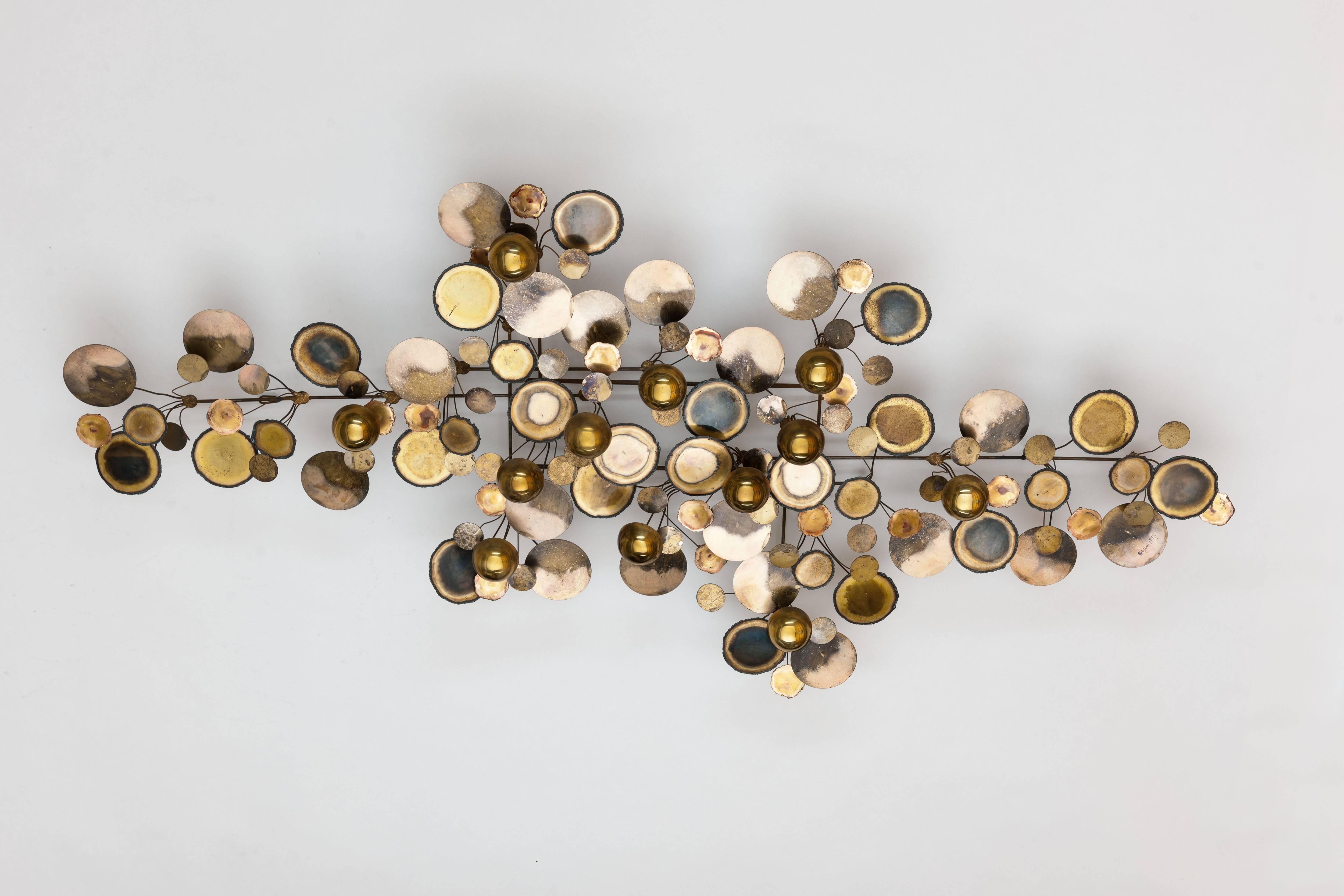Iconic 'Raindrops' wall sculpture by C. Jere / Artisan house, in brass execution.
Abstract metal wall sculpture of torched edge disc's and half spheres made originally between 1965-1979. Object is fully signed including manufacturing year (1975)