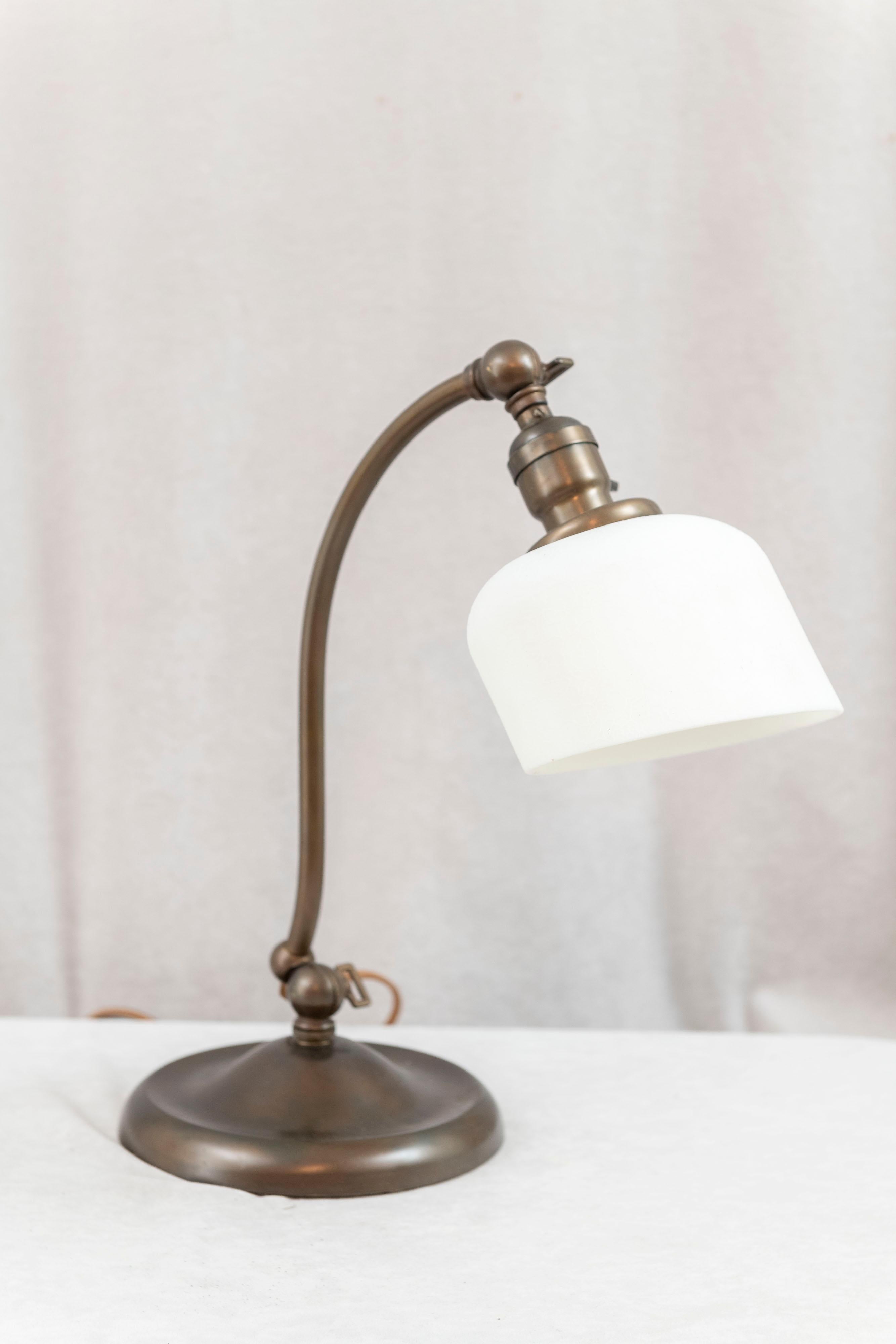  This lamp is both handsome and very practical. It has 2 knuckles up near the top and one near the bottom where you can easily adjust the height and width of the lamp. The brass base is weighted at the bottom and is very stabile. It is nicely