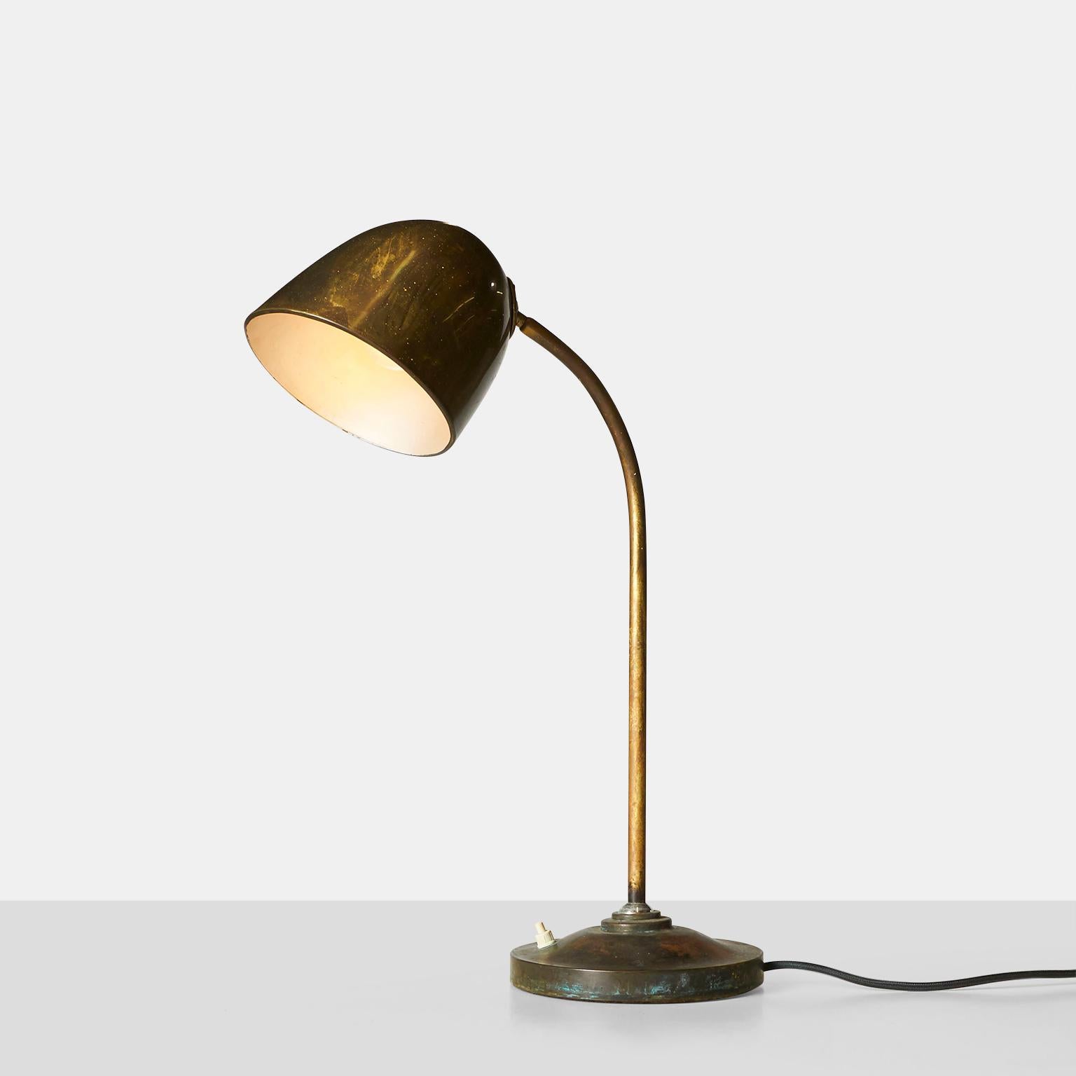 A table lamp of patinated brass, with adjustable and curved neck. Swiveling top and bottom, adjustable in both height and angle. Switch located on the base. 
 