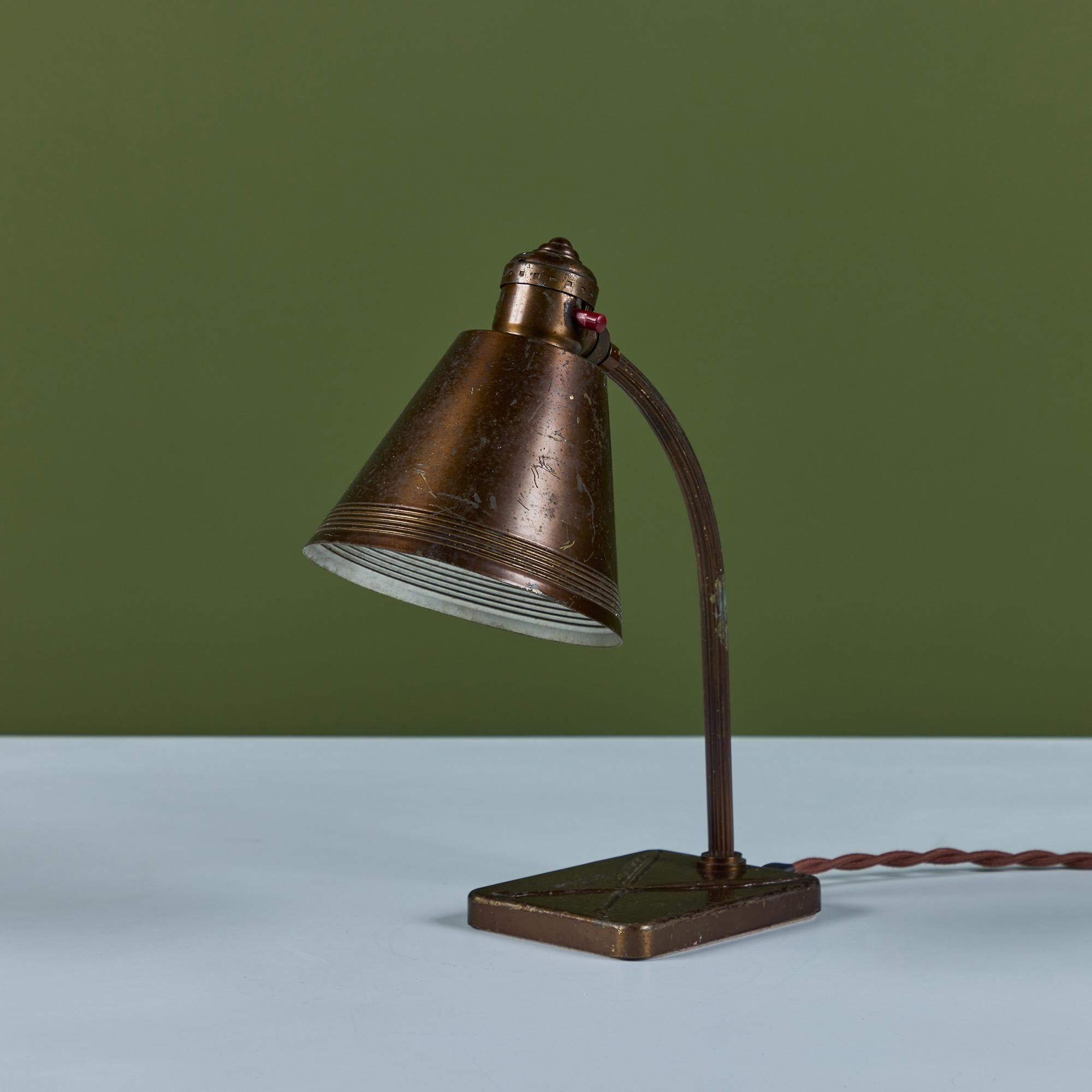 Schreibtischlampe aus Messing für Chase, ca. 1930er Jahre, USA. Die Art-Déco-Lampe hat einen geschwungenen Stiel und einen kegelförmigen Lampenschirm. Die Lampe hat einen rechteckigen Sockel mit zwei ineinandergreifenden Federkielen.

Die Chase