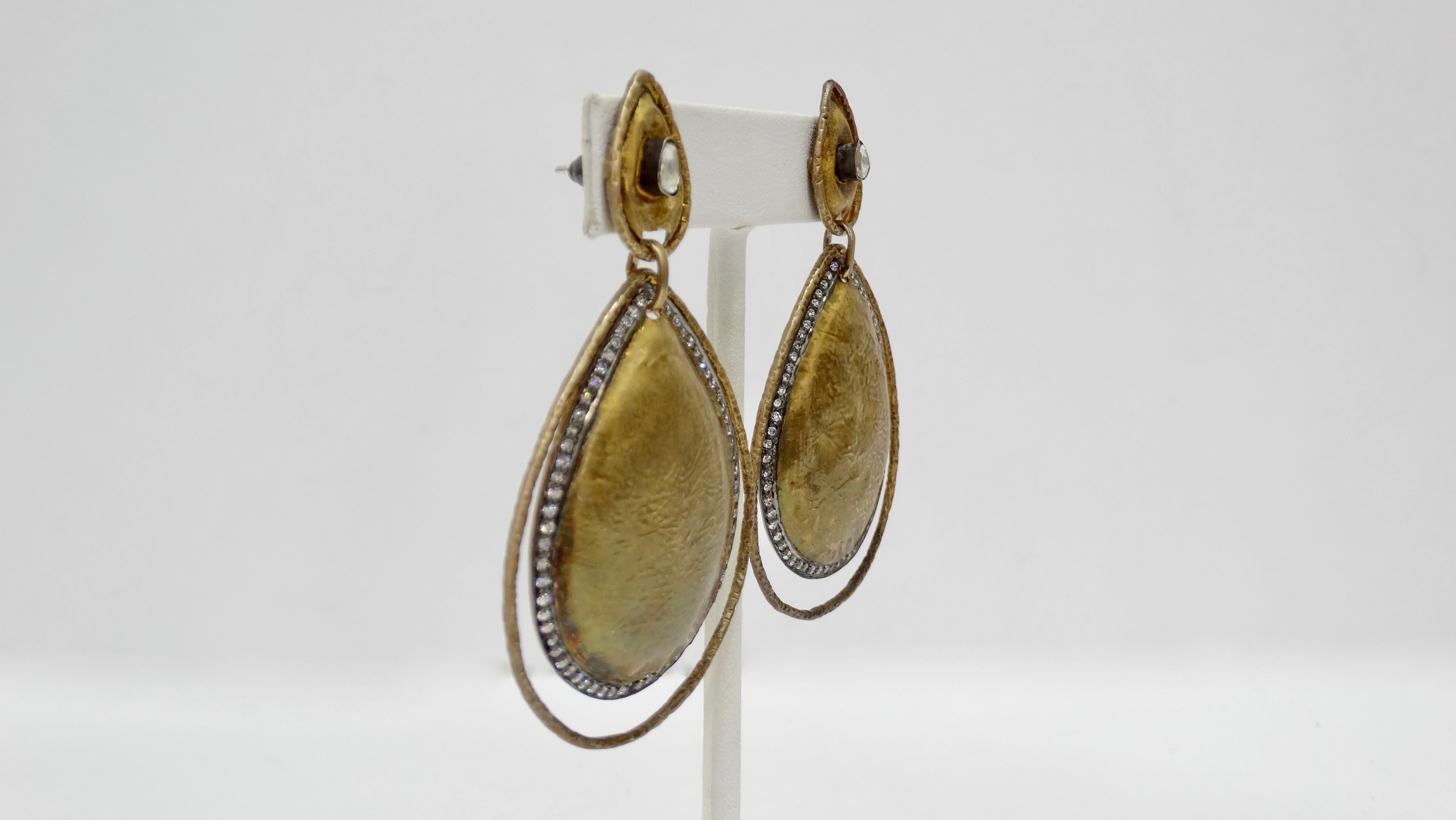 Unique and one of a kind, these late 20th century dangle earrings are crafted from lightly textured Brass and feature a cut out tear drop shape trimmed with surface prong set diamonds, an uncut Diamond at the top of each earring and pierced backs.