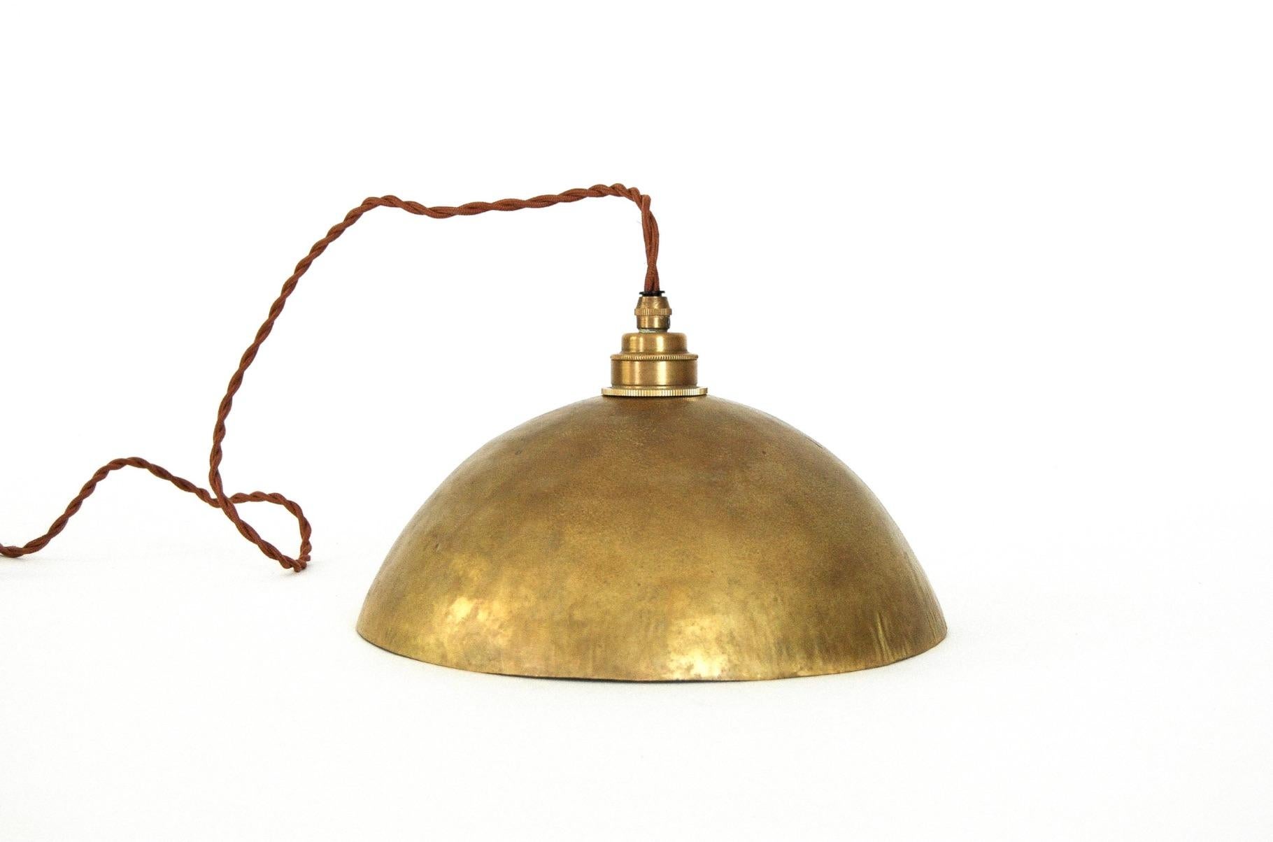 Brass dome pendant lamp with brass socket and braided 12’ cord.  Takes one standard lightbulb.
This beautifully simple hand-forged brass pendant lamp includes a brass socket and an elevated, retro style braided cord that can either come with a plug,