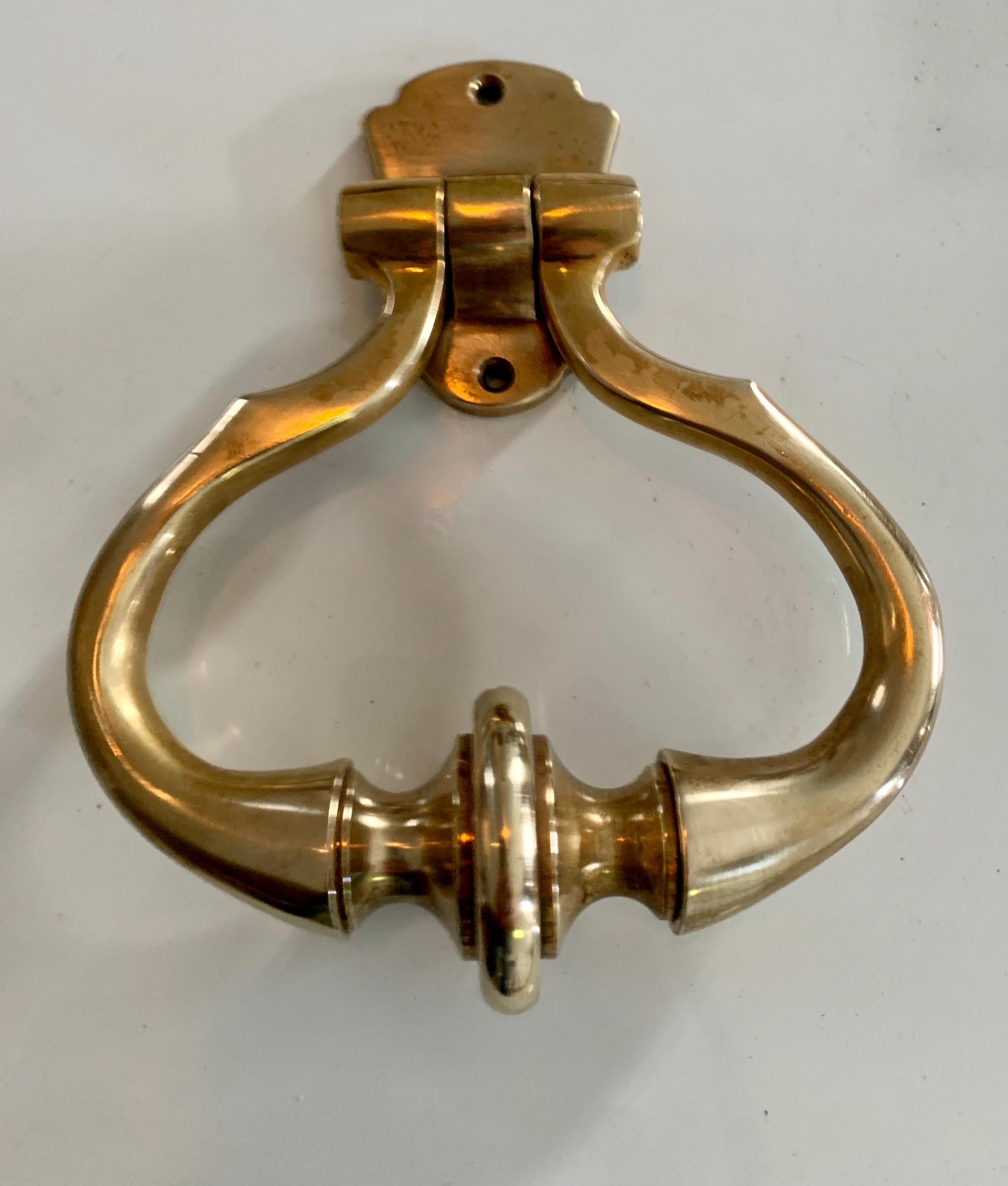 A large brass door knocker. Sophisticated in shape and design. The piece was acquired from an estate in Beverly Hills, CA. A wonderful piece, either or practical use or decor.