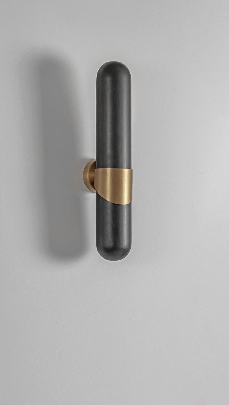 Brass Dream Wall Light by Square in Circle
Dimensions: W 8 x H 45 x D 12 cm.
Materials: brushed brass finish, black powder coated metal.

A cylindrical wall light with rounded edges on both sides, cut at the back to give an ambient glow close to the