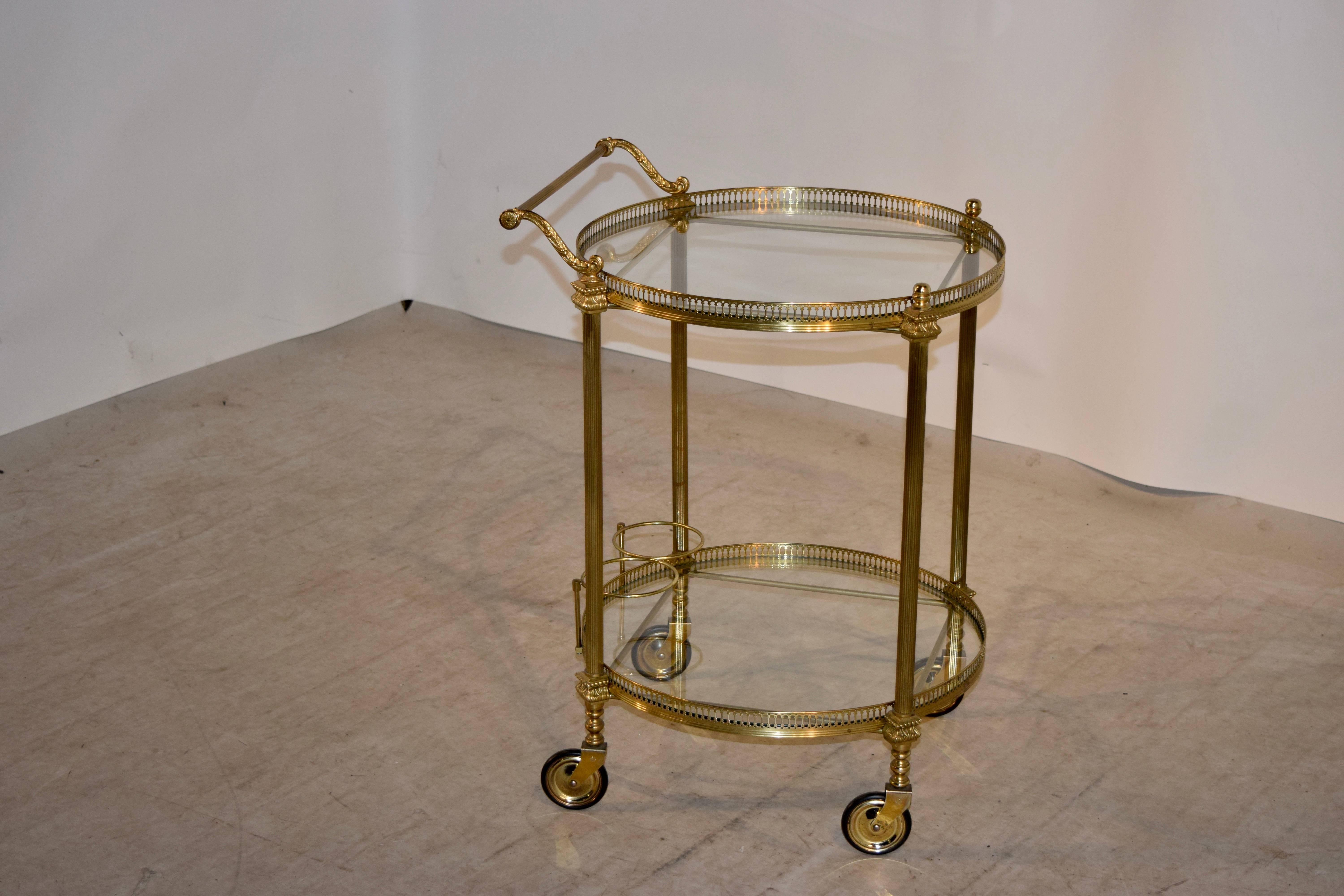 English drinks cart made from brass with glass shelves, circa 1920. The shelves have pierced galleries around them and are connected by fluted columns. It retains its original casters.