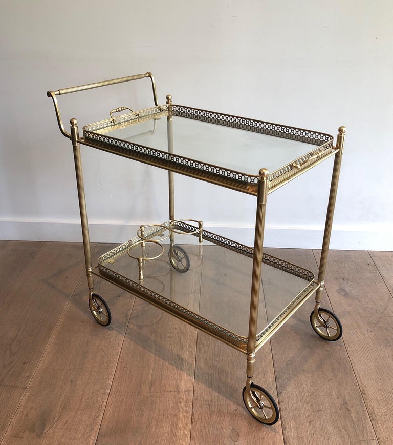 This neoclassical style bar cart is made of brass with  two removable glass trays. This is a work by famous French designer Maison Jansen. Circa 1940
