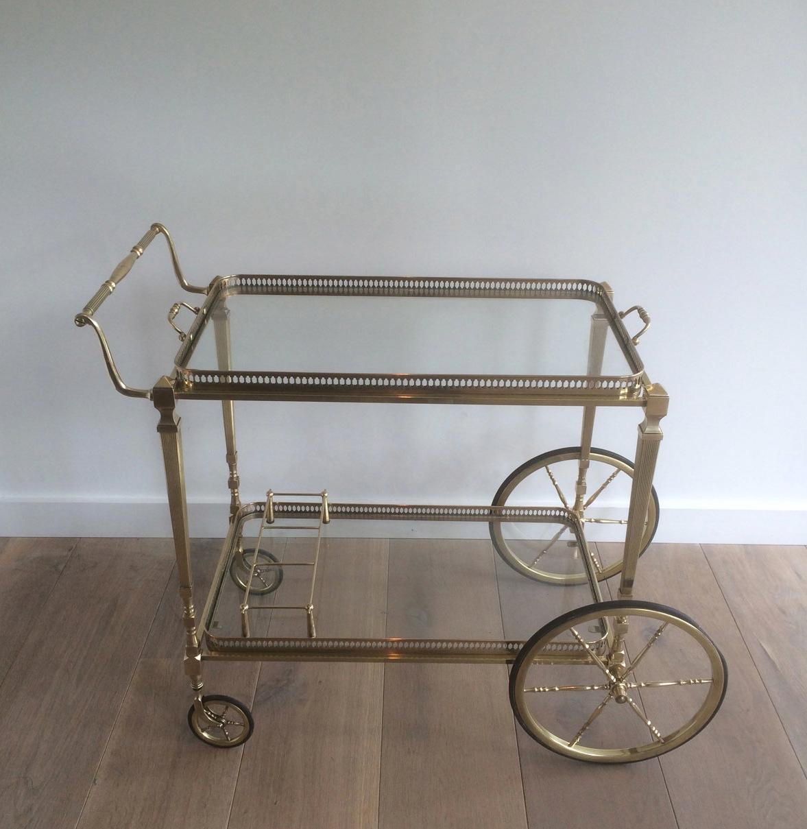 This very elegant neoclassical style drinks trolley is made of brass with removable trays made of a glass shelf surrounded by an openwork brass gallery. This is a French work by Maison Jansen. Circa 1940