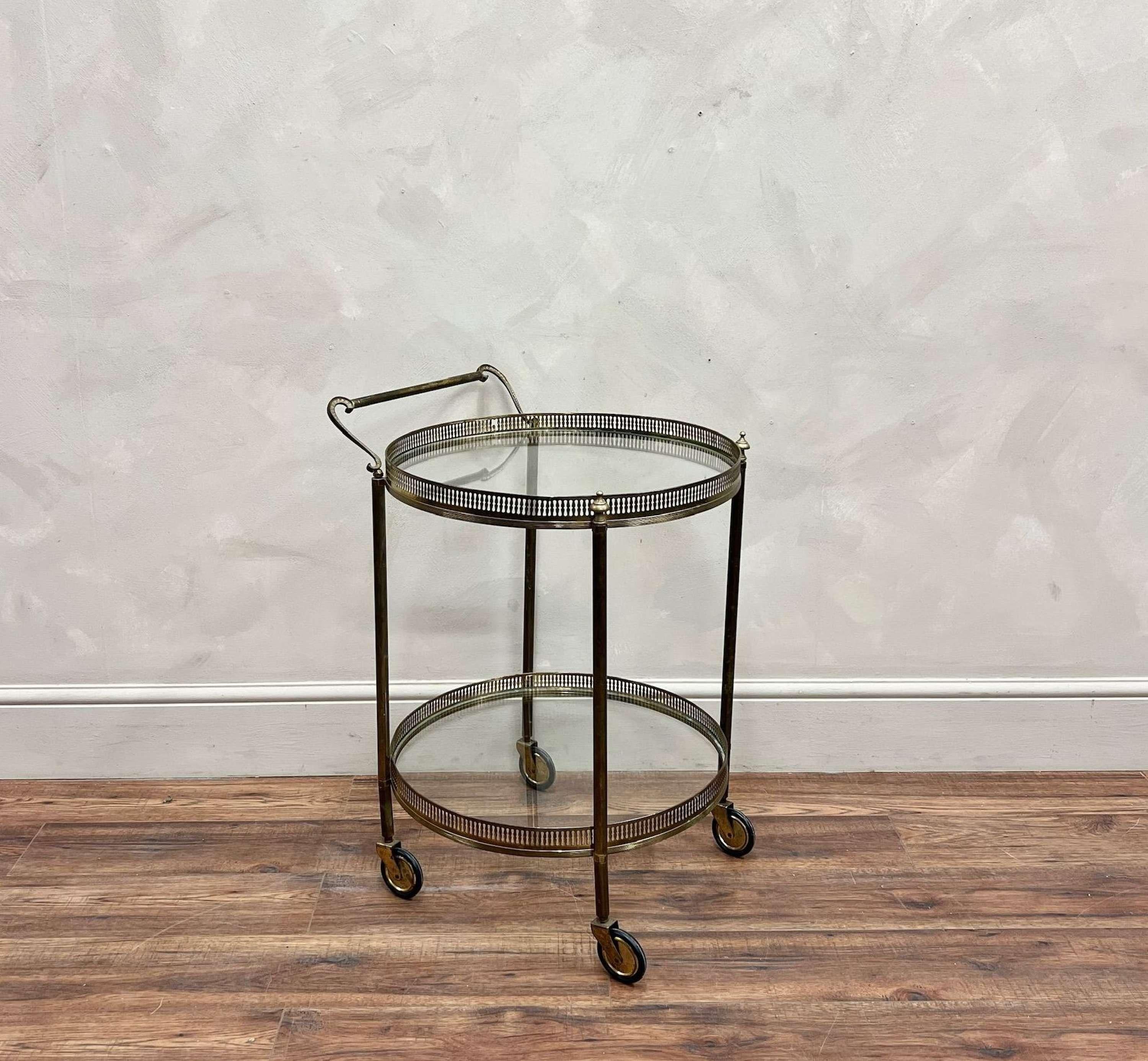 Circular Brass Drinks Trolley.
With toughened glass, pierced gallery, detailed finials, S shaped handle and four sturdy wheels.

Both glass panels have recently been replaced.

France, circa 1940.

Height - 73 cm
Width - 55 cm
Depth - 53 cm

Please