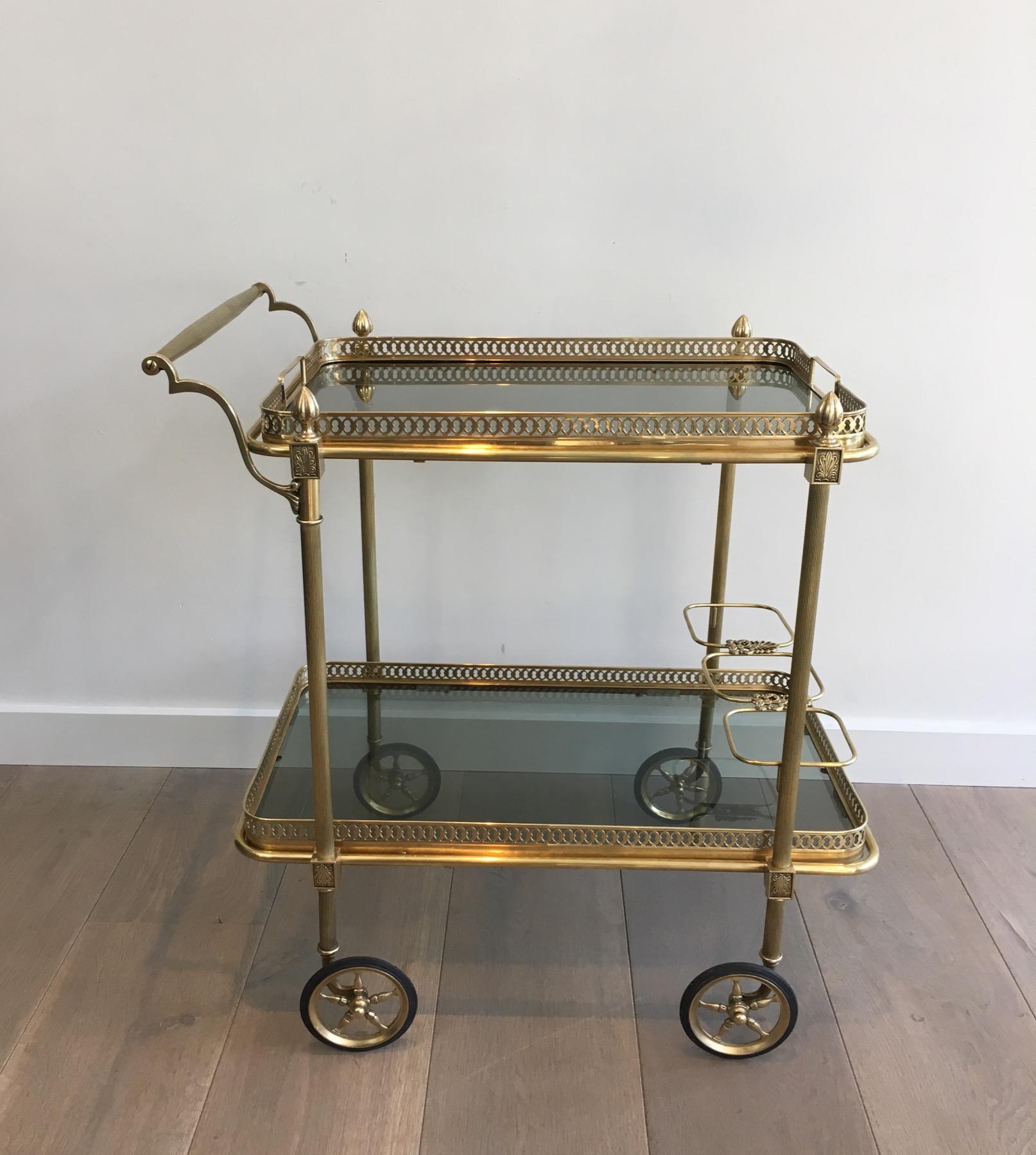 This very nice and elegant neoclassical style drinks trolley is made of brass with blueish glass shelves. Top tray is removable and can be used to present drinks, bottles or others. This is a French work by Maison Jansen. Circa 1940