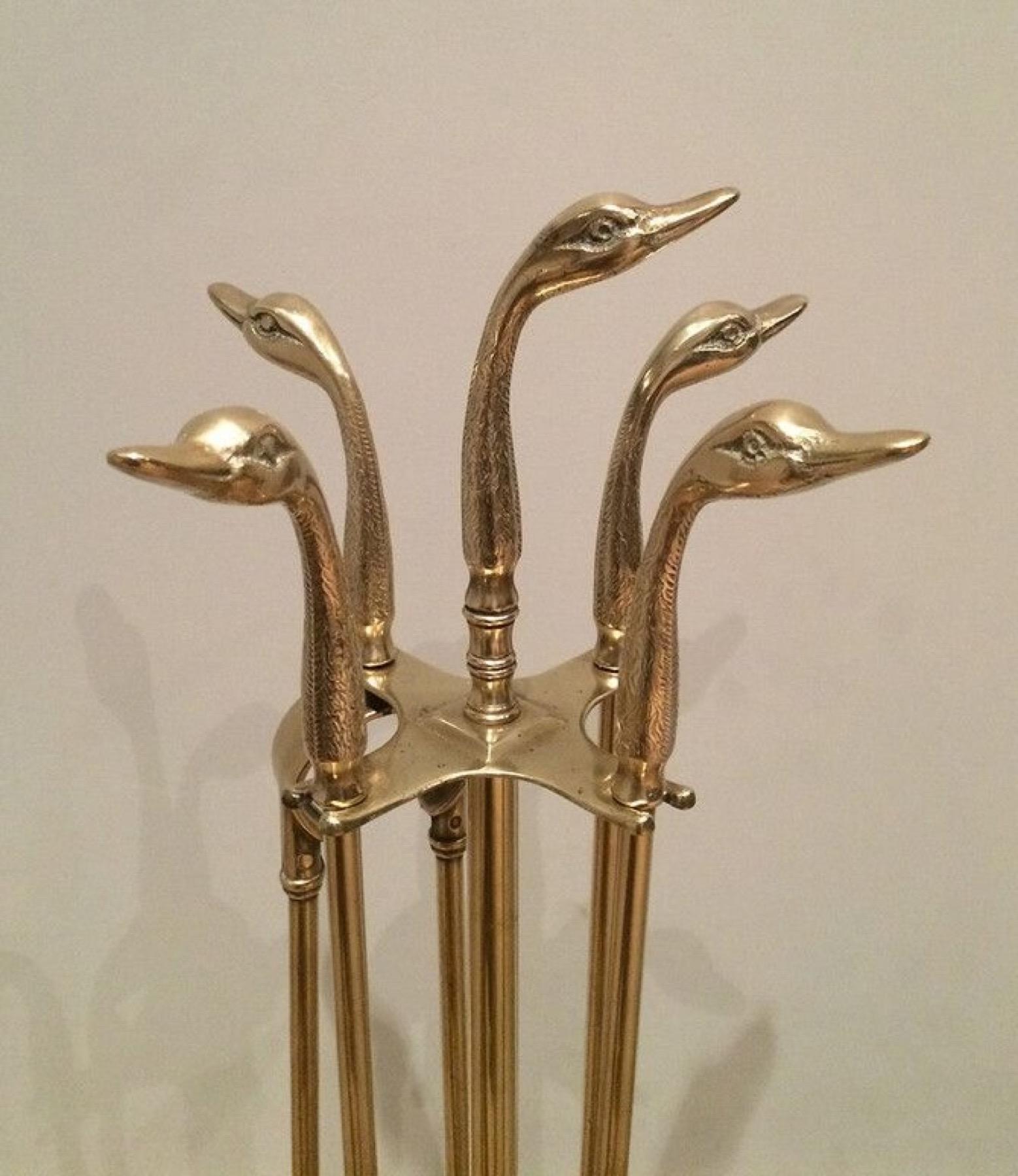 This very nice and elegant pair of fireplace tools on stand is all made of brass. It is ornated with brass duck heads. This is a French work in the Style of Maison Jansen. Circa 1940