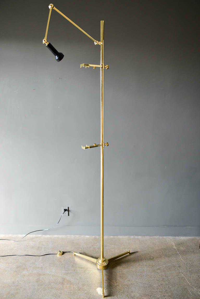 Brass easel lamp by Angelo Lelli for Arredoluce of Italy, circa 1960. Beautiful original condition with foot switch and illuminated adjustable spotlight. Articulating arms and adjustable brackets can hold nearly any size of artwork. Polished brass,